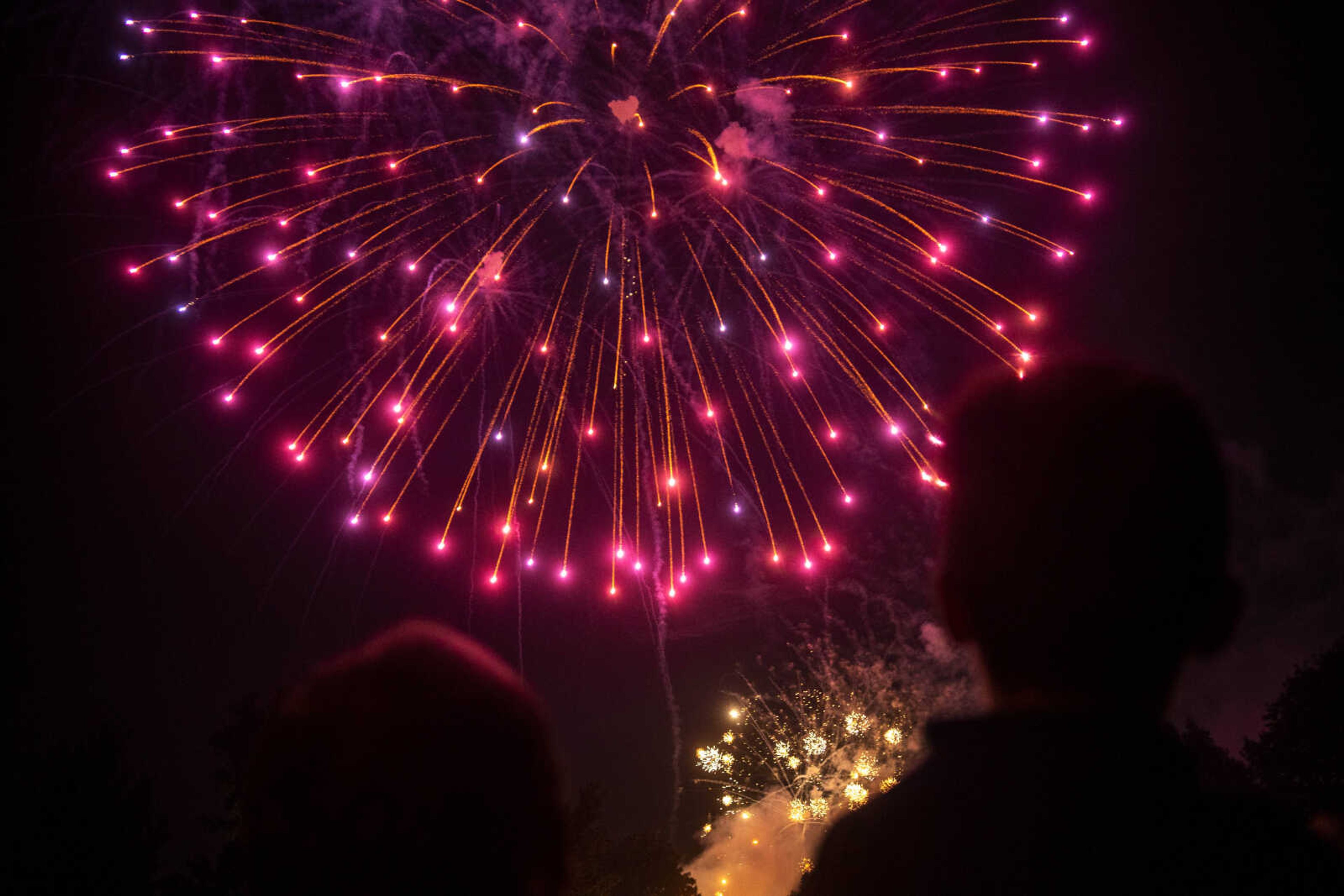 Josh Martin, left, and his nephew, Isaiah Dunavan, right, are silhouetted by fireworks during an Independence Day celebration at the Jackson Municipal Band Shell.