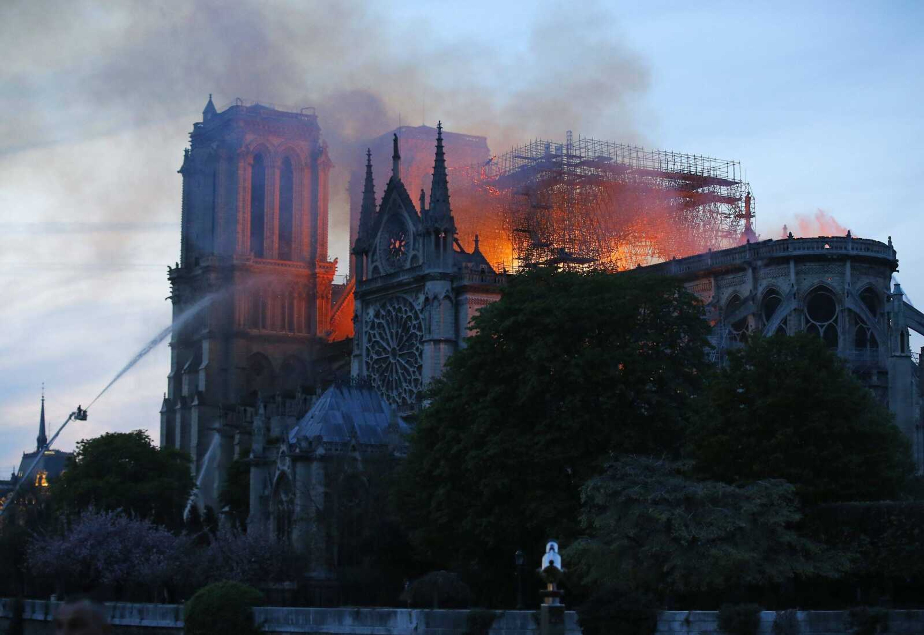 A firefighter tackles the blaze as flames and smoke rise from Notre Dame cathedral as it burns in Paris, Monday, April 15, 2019. Massive plumes of yellow brown smoke is filling the air above Notre Dame Cathedral and ash is falling on tourists and others around the island that marks the center of Paris. (AP Photo/Michel Euler)