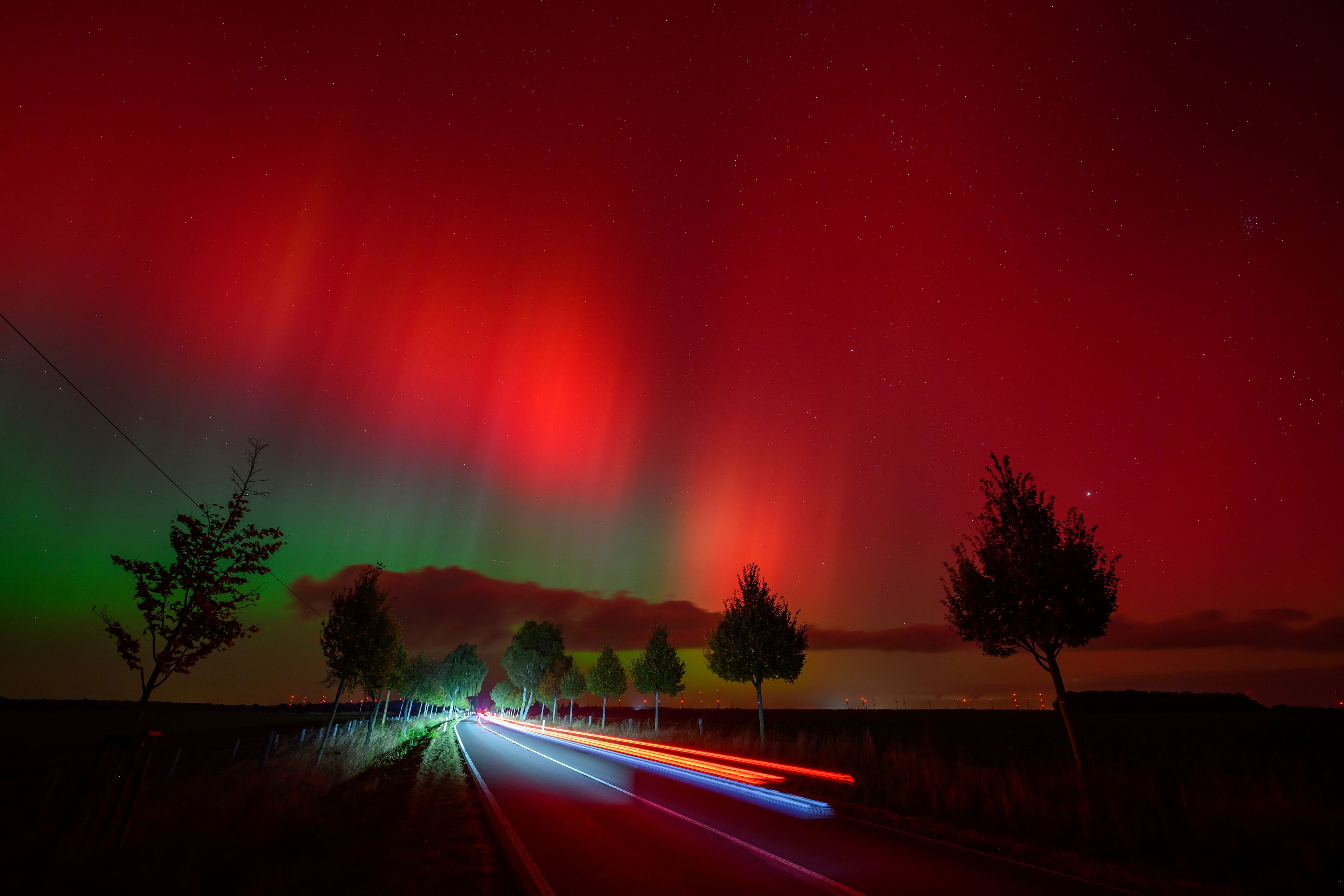 An aurora borealis, also known as the northern lights, glows in the night sky above a road in Lietzen, eastern Germany. (Patrick Pleul/dpa via AP)