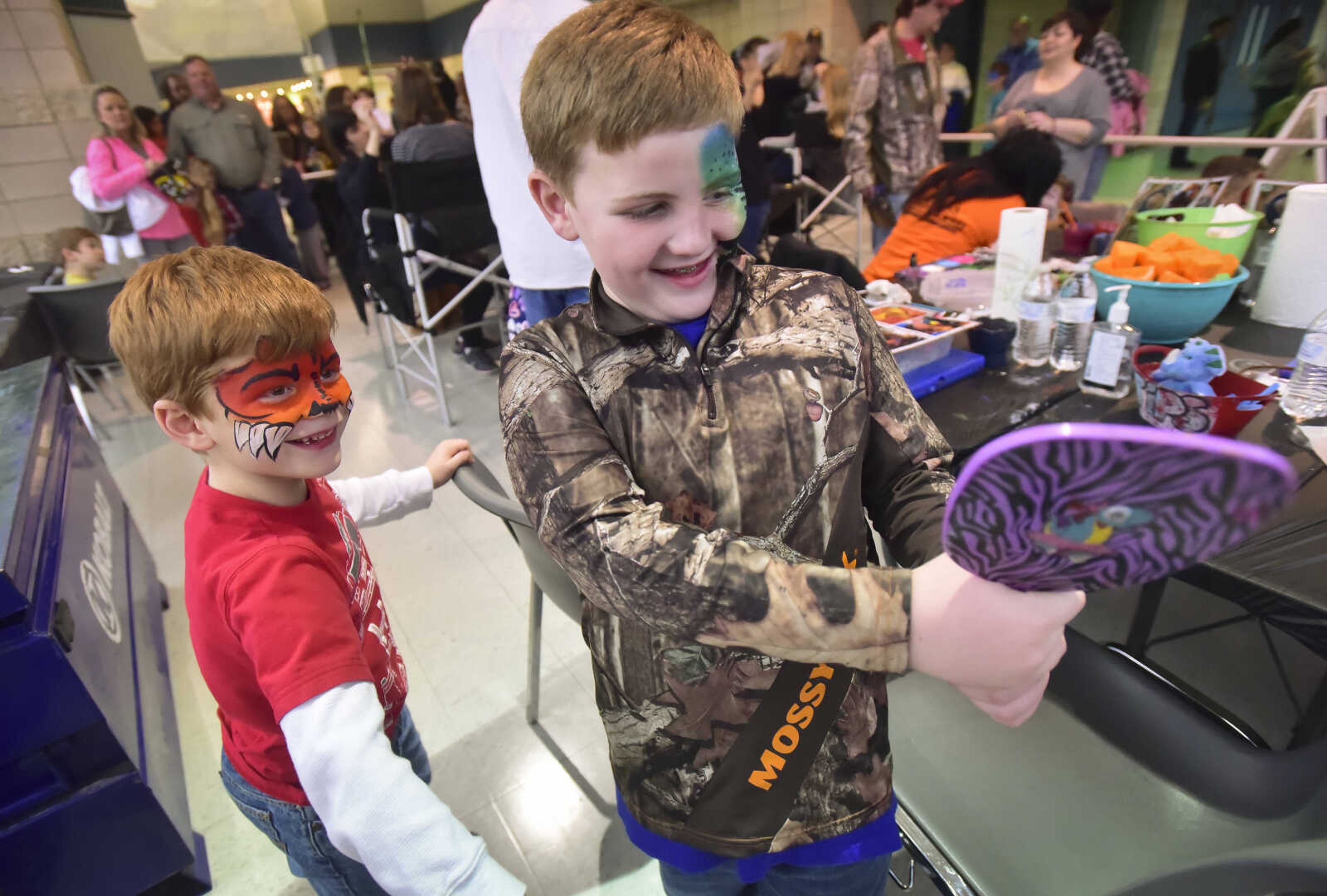 Aiden Bailey, 7, and Bennett Rolwing, 7, look in a mirror after getting their face painted during Jurassic Quest Saturday, Jan. 14, 2017 at the Show Me Center in Cape Girardeau.