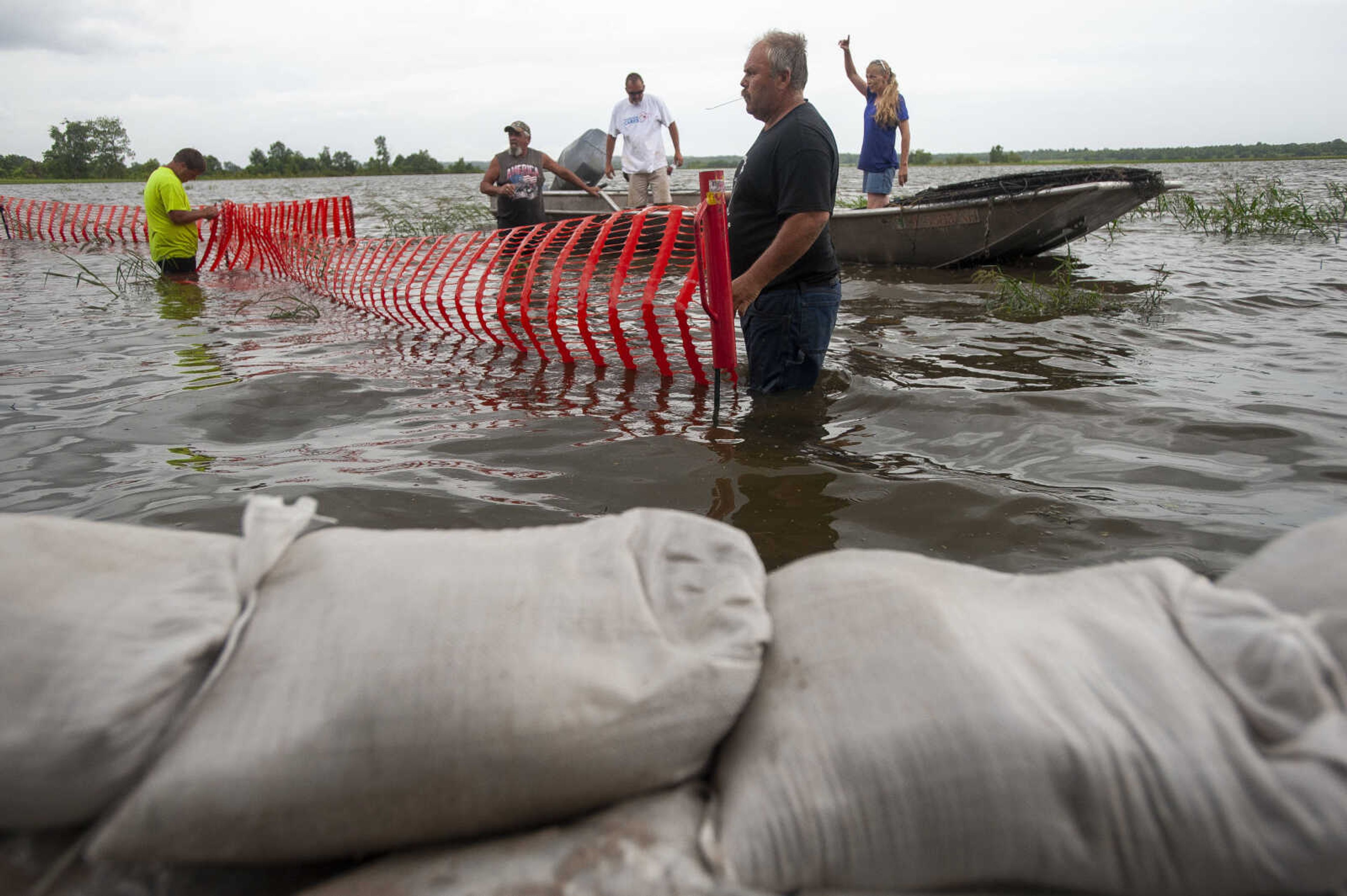 Stacy Gilpin, center foreground, of Niota, Illinois, helps residents of East Cape Girardeau, Illinois, including, back from left, Toby Warner, Shawn Merritt, Rick Smith and Ashley Sturm, install a barrier to help slow waves on the floodwaters before the waves hit sandbag walls, in foreground, on Sunday, July 14, 2019, along the south side of East Cape Girardeau. Although not from East Cape Girardeau, Gilpin's daughter lives in the community. "My daughter's here. I'm just here to help," he said.