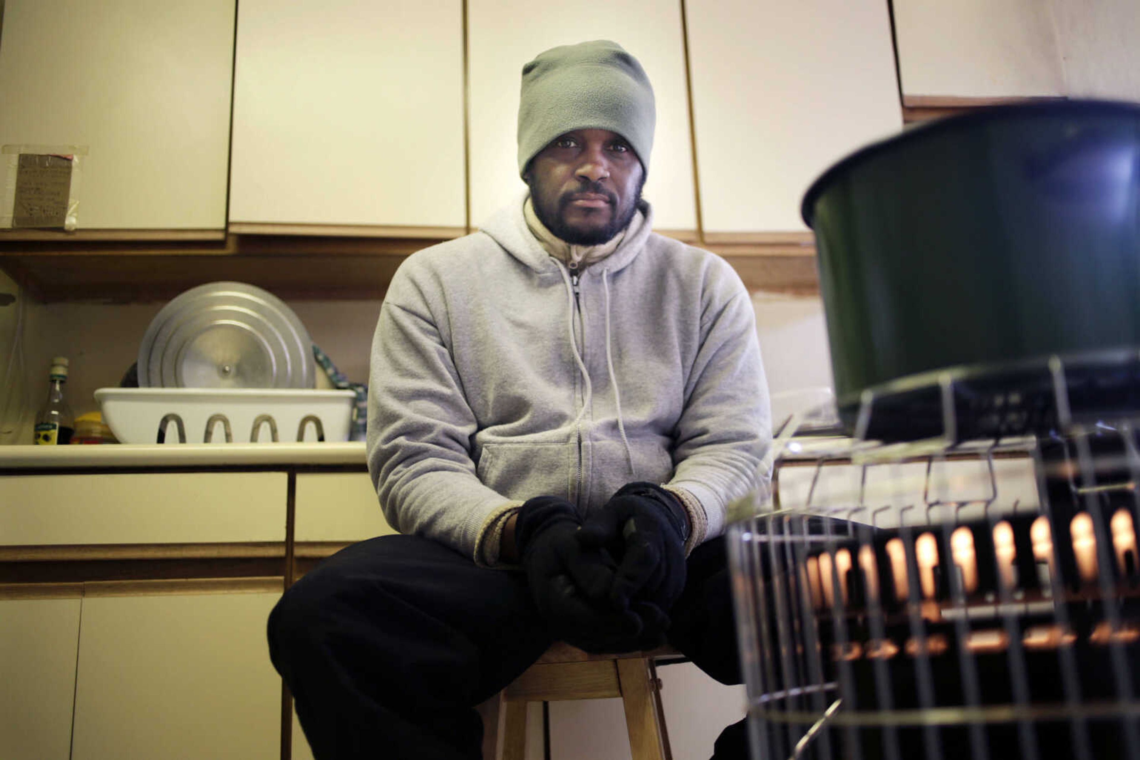 In this Jan. 27, 2013 photo, Devon Lawrence poses for a picture in his kitchen, which is currently heated by a kerosene heater and his stove top, in the Far Rockaway neighborhood of New York. Lawrence hasn't had working heat since Superstorm Sandy's floodwaters destroyed the oil burner in the basement. Three months after Sandy struck, thousands of storm victims in New York and New Jersey are stuck in limbo. Waiting for the heat to come on, for insurance money to come through, for loans to be approved. Waiting, in a broader sense, for their upended lives to get back to normal.  (AP Photo/Seth Wenig)