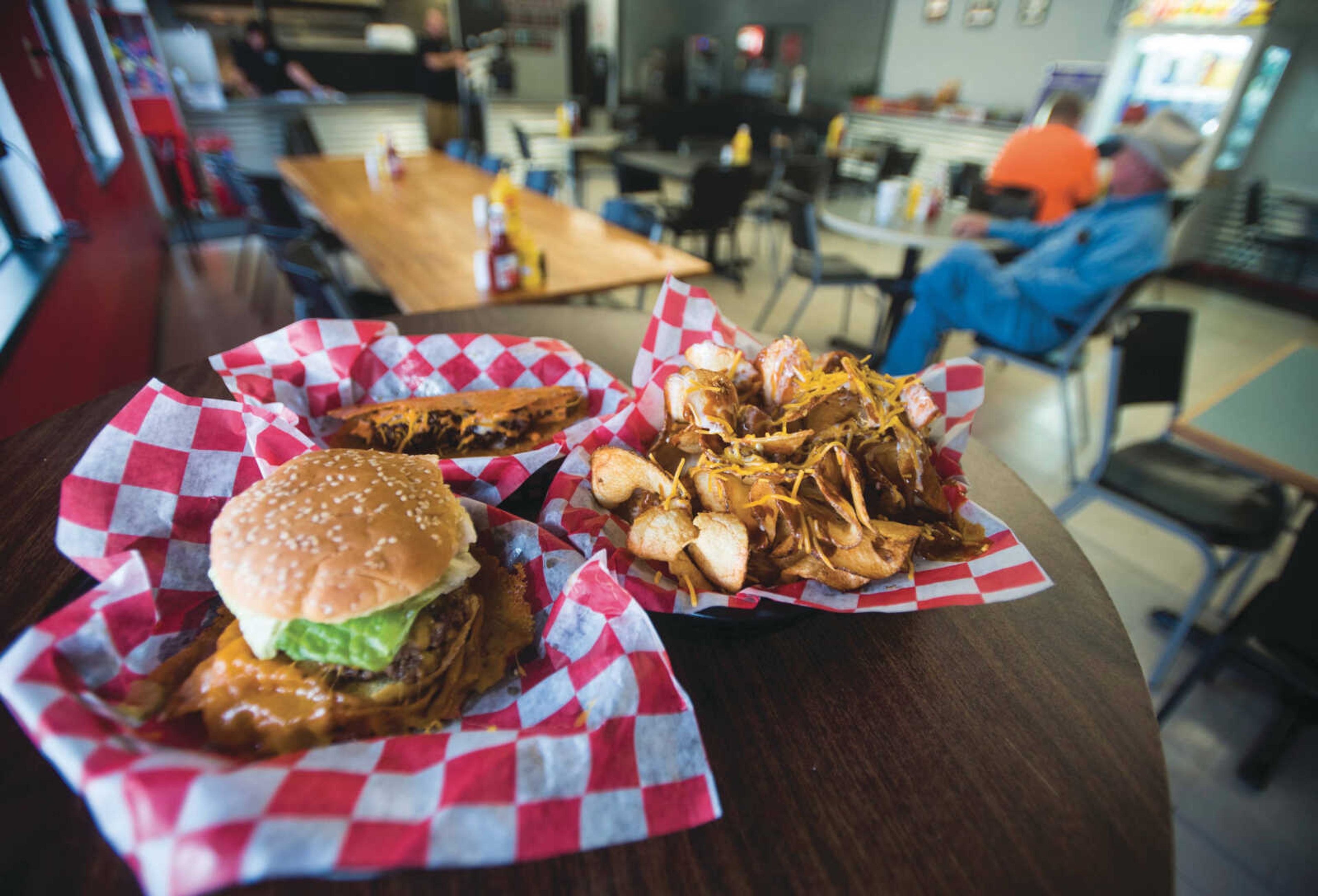 BEN MATTHEWS ~ bmatthews@semissourian.com A taco burger sits behind a Holy Flippin' Cheeseburger and an order of ribbon fries Sept. 18, 2017 at Kenny's Flippin' Burgers in Chaffee.