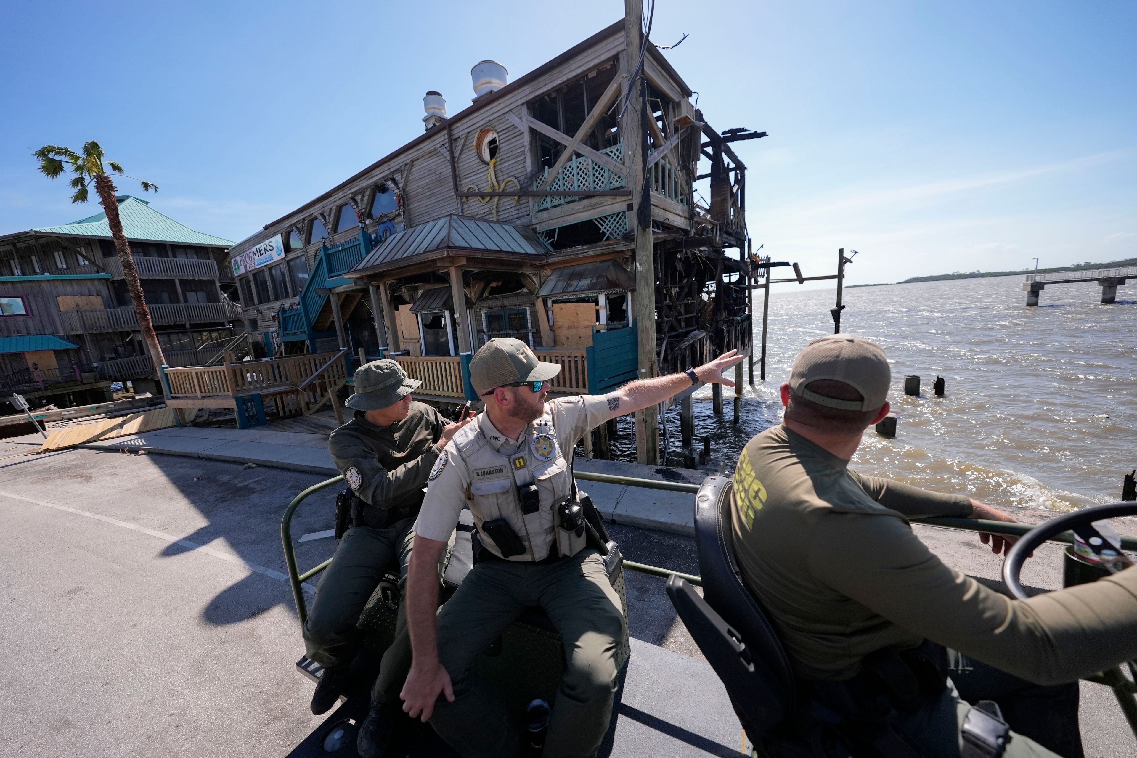 Officer Nate Martir, left, Capt. BJ Johnston and Lieutenant Kevin Kleis, law enforcement officers from the Florida Fish Wildlife and Conservation Commission drive past destruction in a high water capable swamp buggy, in the aftermath of Hurricane Helene, in Cedar Key, Fla., Friday, Sept. 27, 2024. (AP Photo/Gerald Herbert)