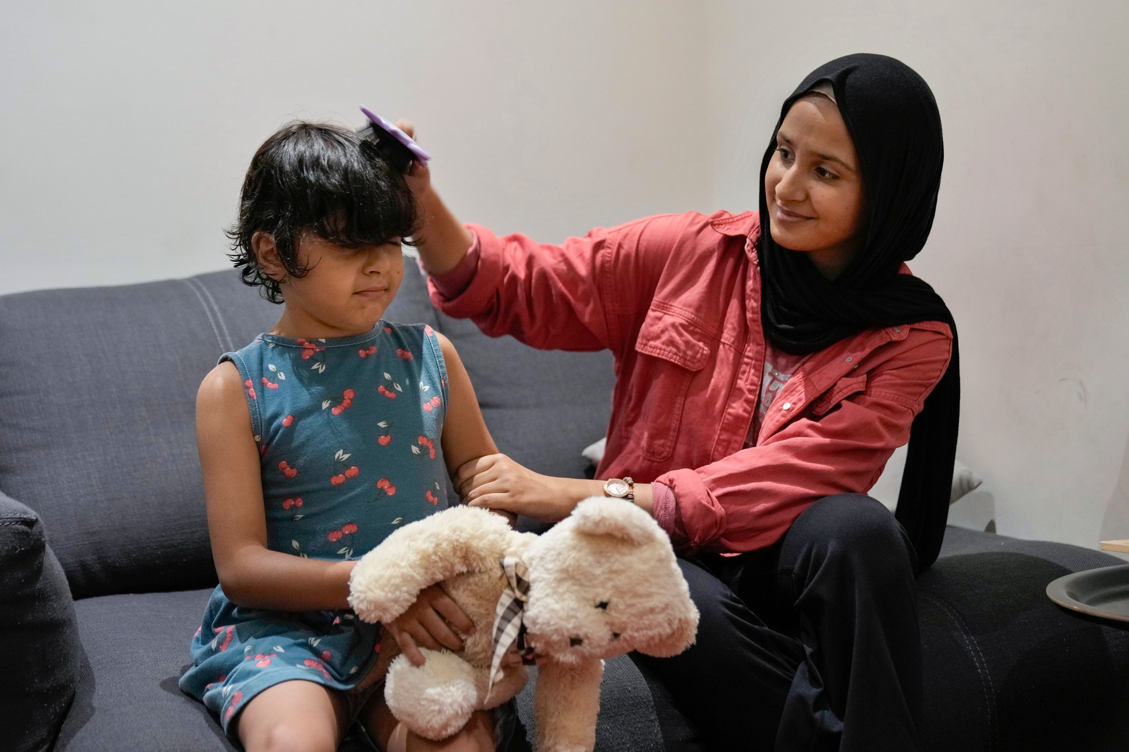 Siwar Abou Yassine, right, combs the hair of her sister Halima, 7, who was brought to Lebanon from Gaza for treatment after an Israeli strike left her near death with a gaping wound in her skull, in Beirut, Lebanon, Friday, Aug. 30, 2024. (AP Photo/Bilal Hussein)