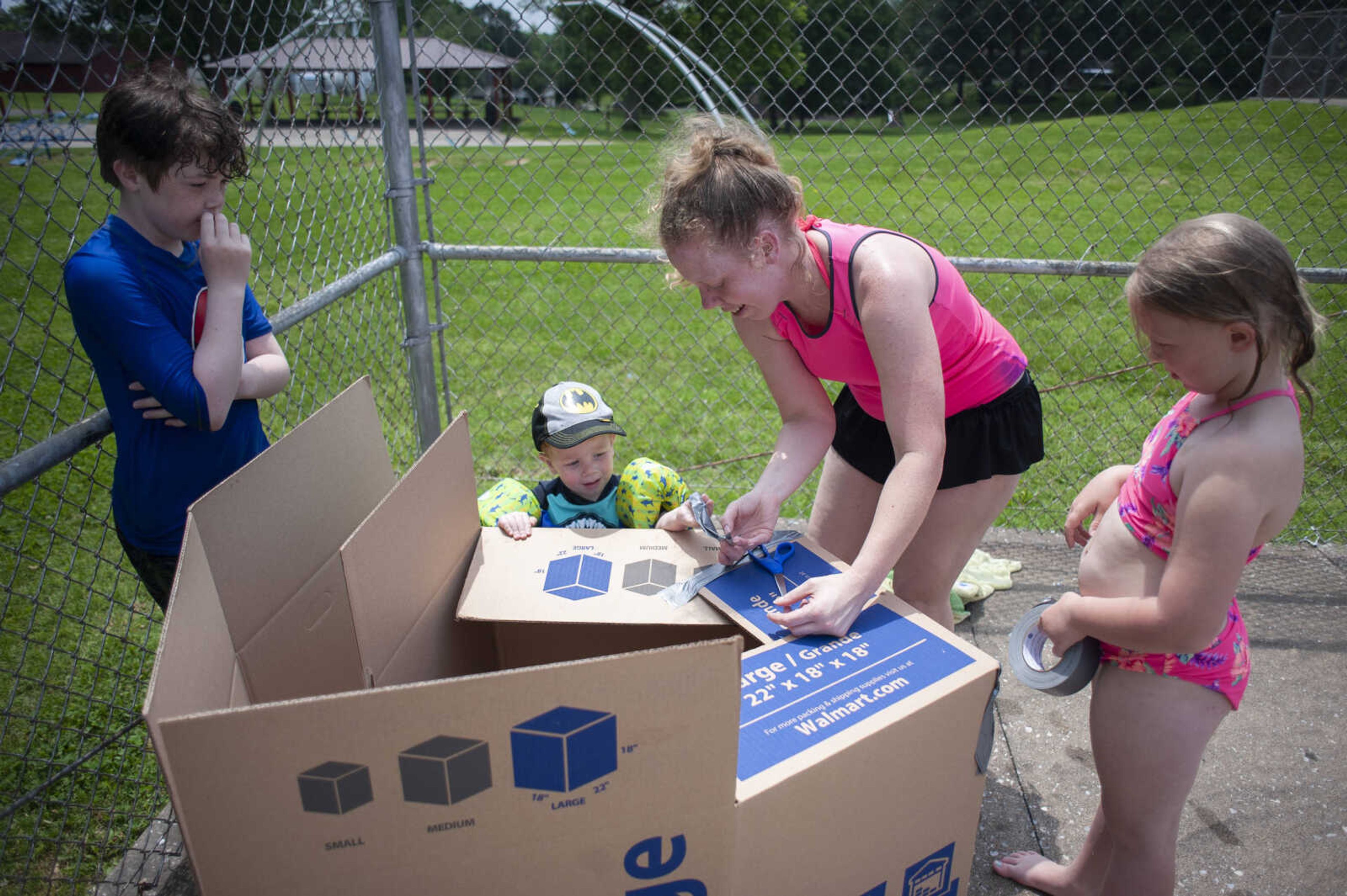 Ashley Geiser of Scott City, second from right, and her daughter Abigail Geiser, 7, work to construct a cardboard boat next to Ashley's sons Emmet Zurbriggen, 2, and Dylan Gibson, 12, before a cardboard boat contest during a free pool party to start off the 2019 season Saturday, May 25, 2019, at the&nbsp;Scott City Community Pool.