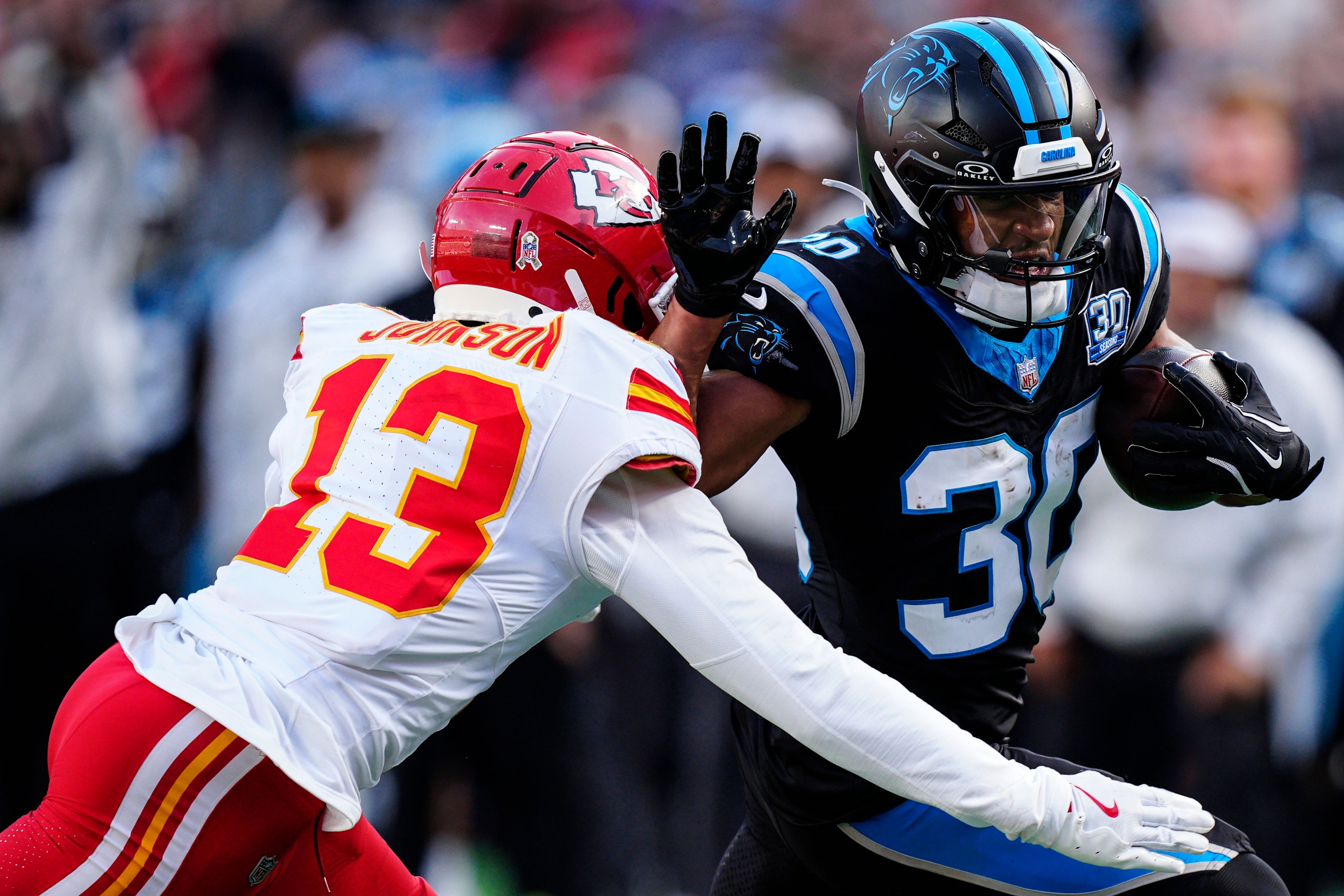 Carolina Panthers running back Chuba Hubbard (30) runs against Kansas City Chiefs safety Nazeeh Johnson (13) during the second half of an NFL football game, Sunday, Nov. 24, 2024, in Charlotte, N.C. (AP Photo/Jacob Kupferman)