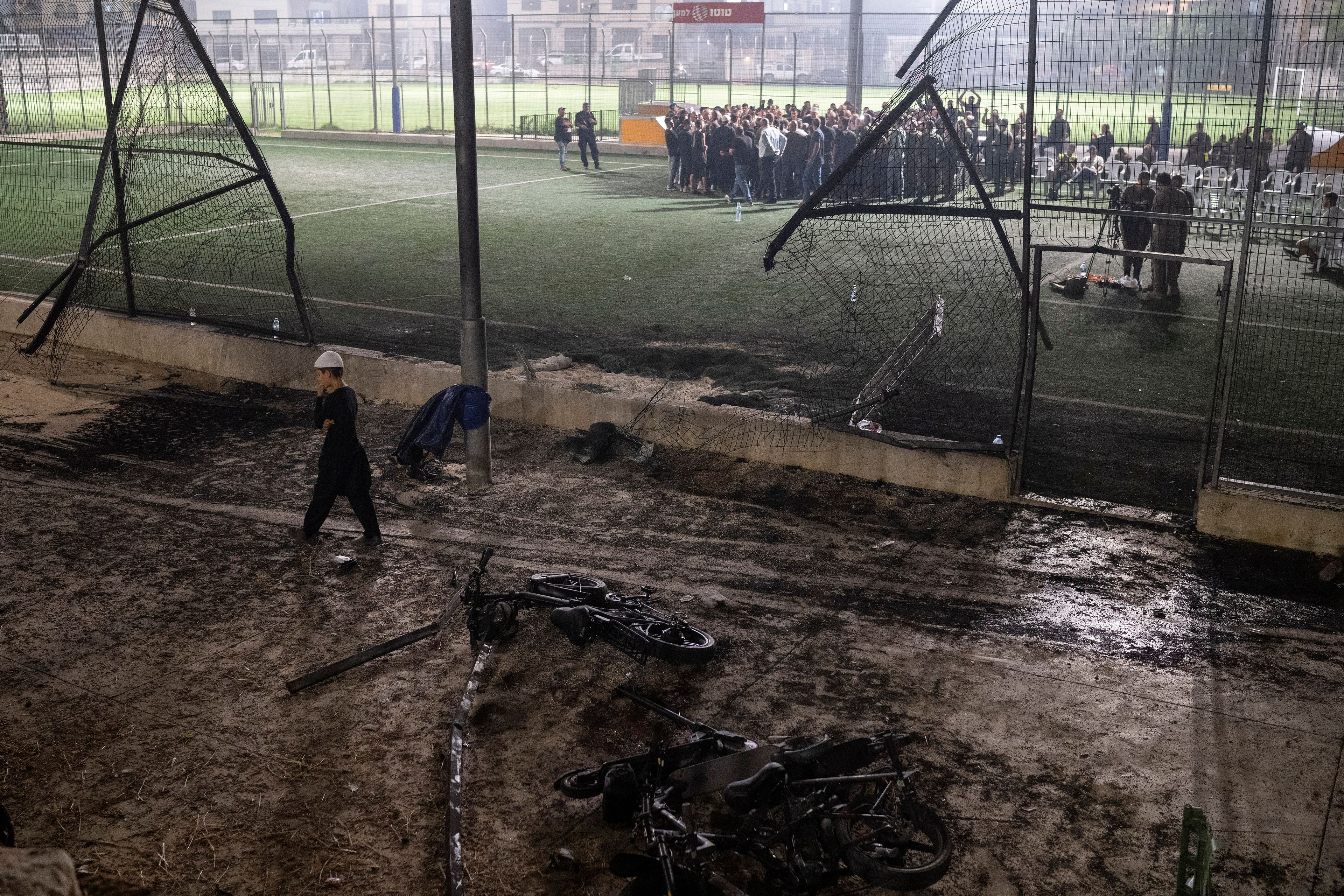 A boy walks past bicycles left next to the area that was hit by a rocket, killing multiple children and teenagers, on a soccer field in the Druze town of Majdal Shams, in the Israeli-annexed Golan Heights, Saturday, July 27, 2024. (AP Photo/Leo Correa)