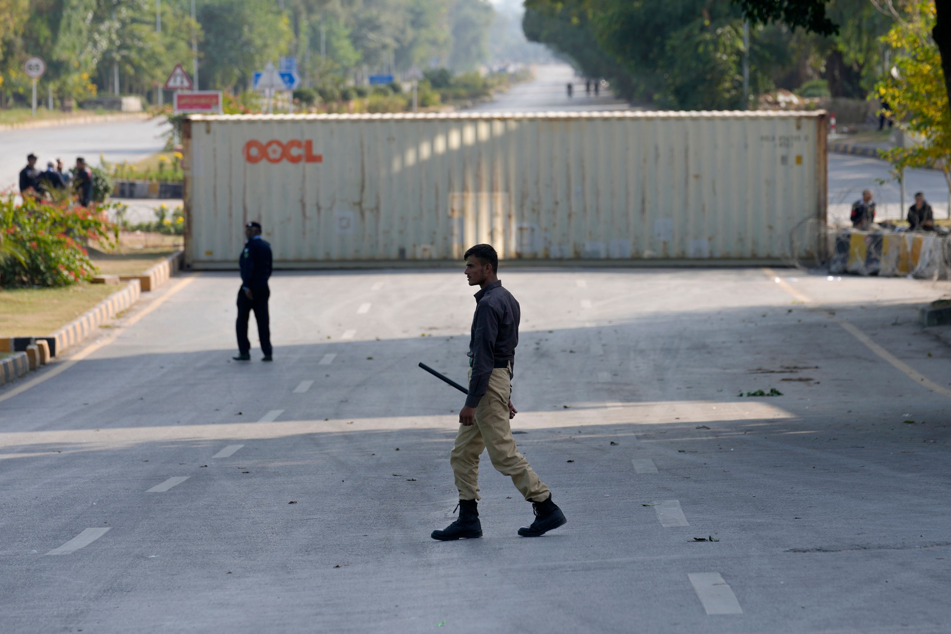 Police officers patrol at a road barricaded with shipping containers ahead of a planned rally by supporters of imprisoned former Prime Minister Imran Khan's Pakistan Tehreek-e-Insaf party, in Islamabad, Pakistan, Sunday, Nov. 24, 2024. (AP Photo/Anjum Naveed)