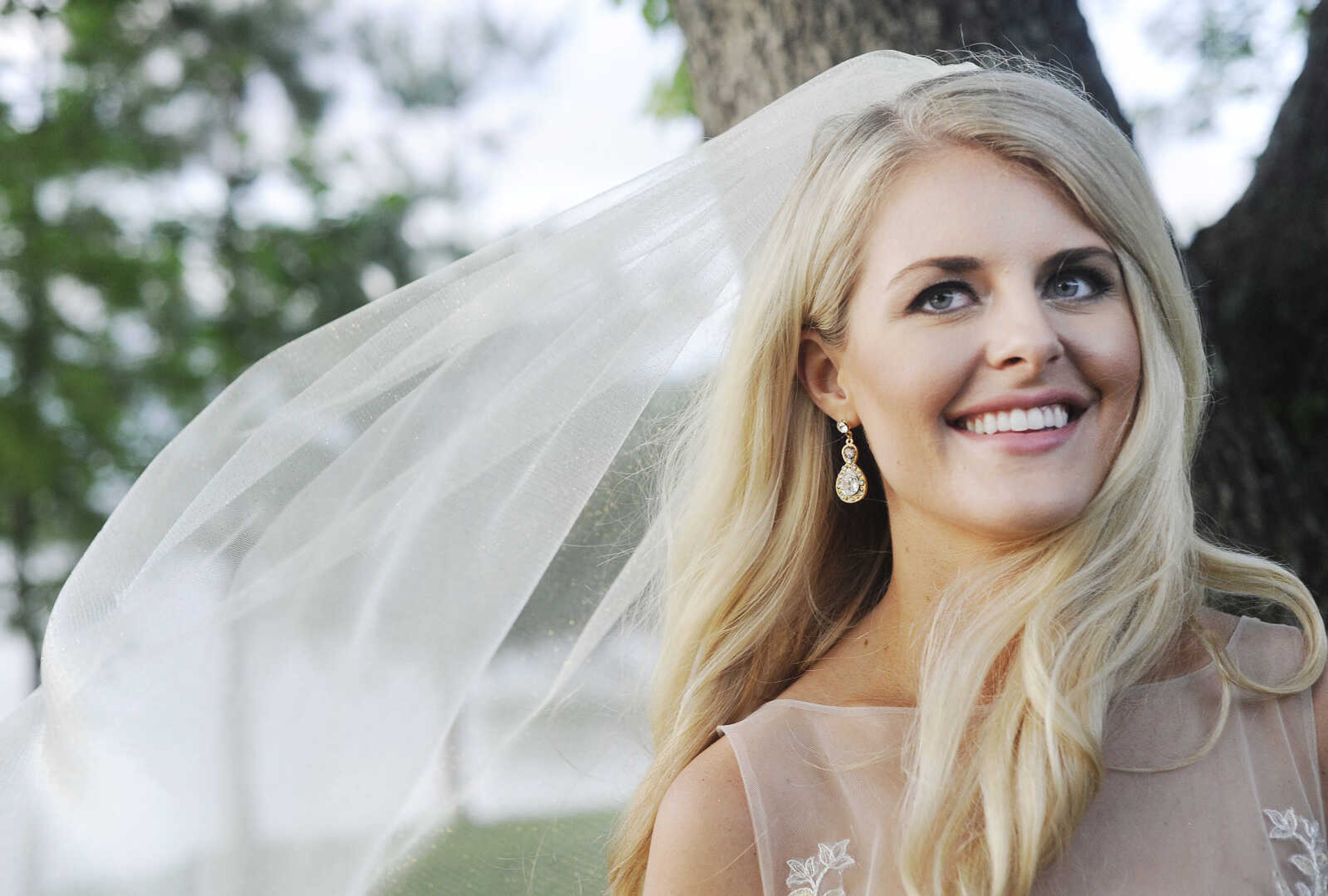 On Paige: This Tara Keely ballgown in ivory gold has an illusion scoop neckline, a V-back with cascading lace detail and an asymmetrical tiered skirt. The gown is accessorized with a glitzy gold belt and sparkle illusion cathedral-length veil, both by Lindsay Marie. Dress and accessories available at Magnolias Bridal Boutique in Cape Girardeau.