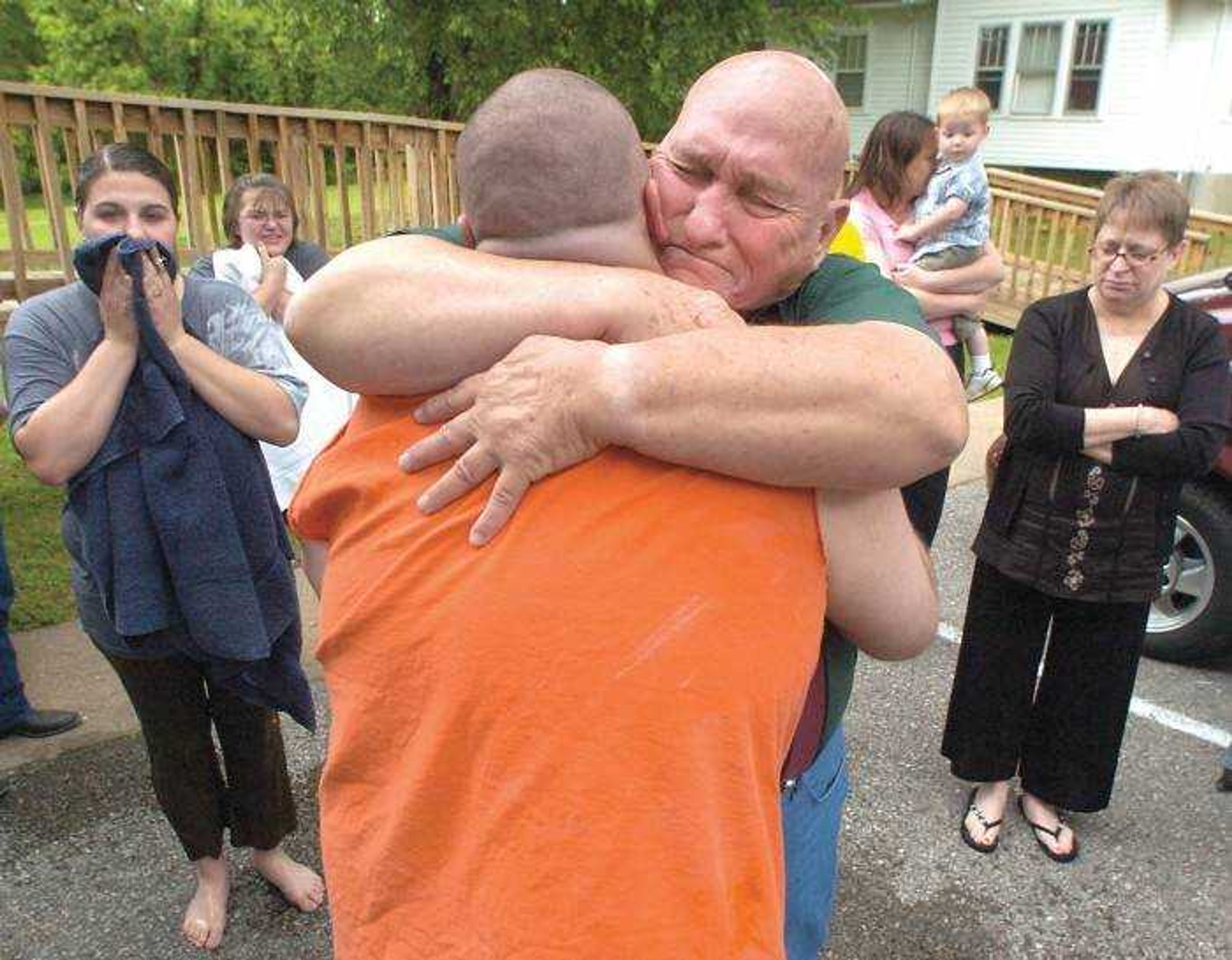 The Rev. Bob Murray gave David Depoister a heart-felt embrace before baptizing him Sunday at Holy Spirit Harvest Church in Cape Girardeau. Among those gathered were Depoister's fiance, Megan Adamson, left, who had just been baptized, and Murray's wife, Paula, right. (Fred Lynch)