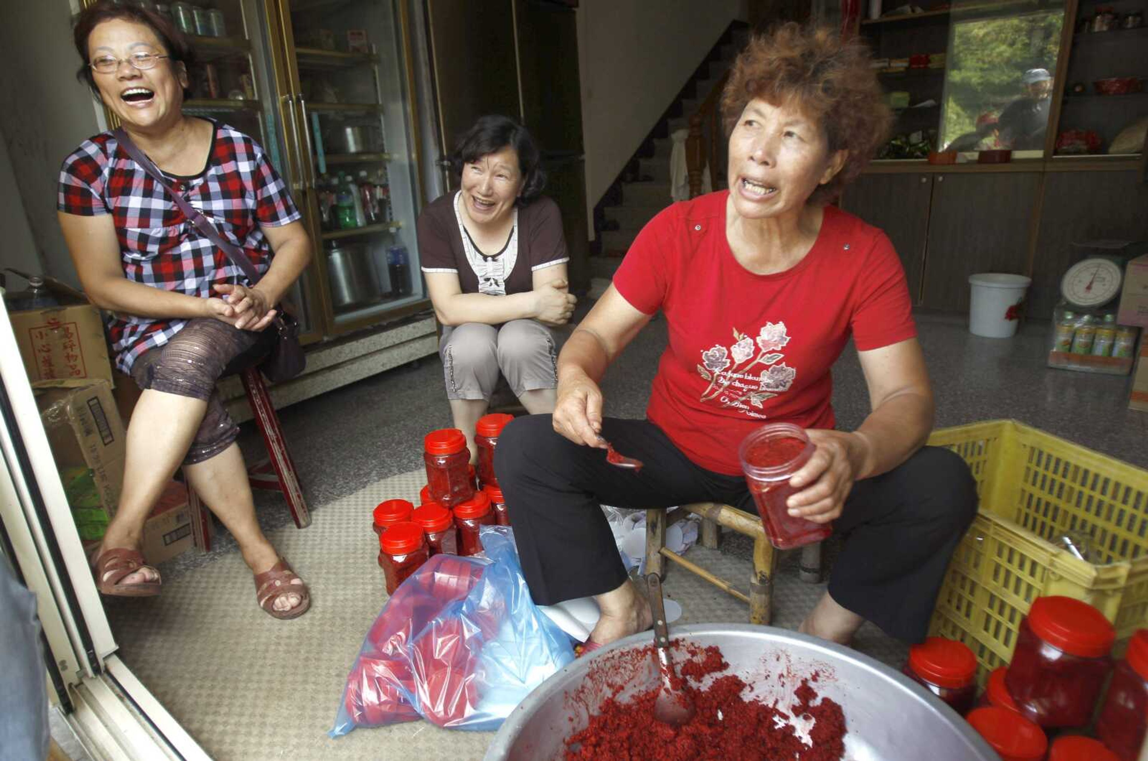 Island residents fill jars of red sorghum, a local delicacy, on Aug. 21 and talk about why they voted for the proposed casino to be built on Beigan in the Matsu island group, off northern Taiwan. (Wally Santana ~ Associated Press)