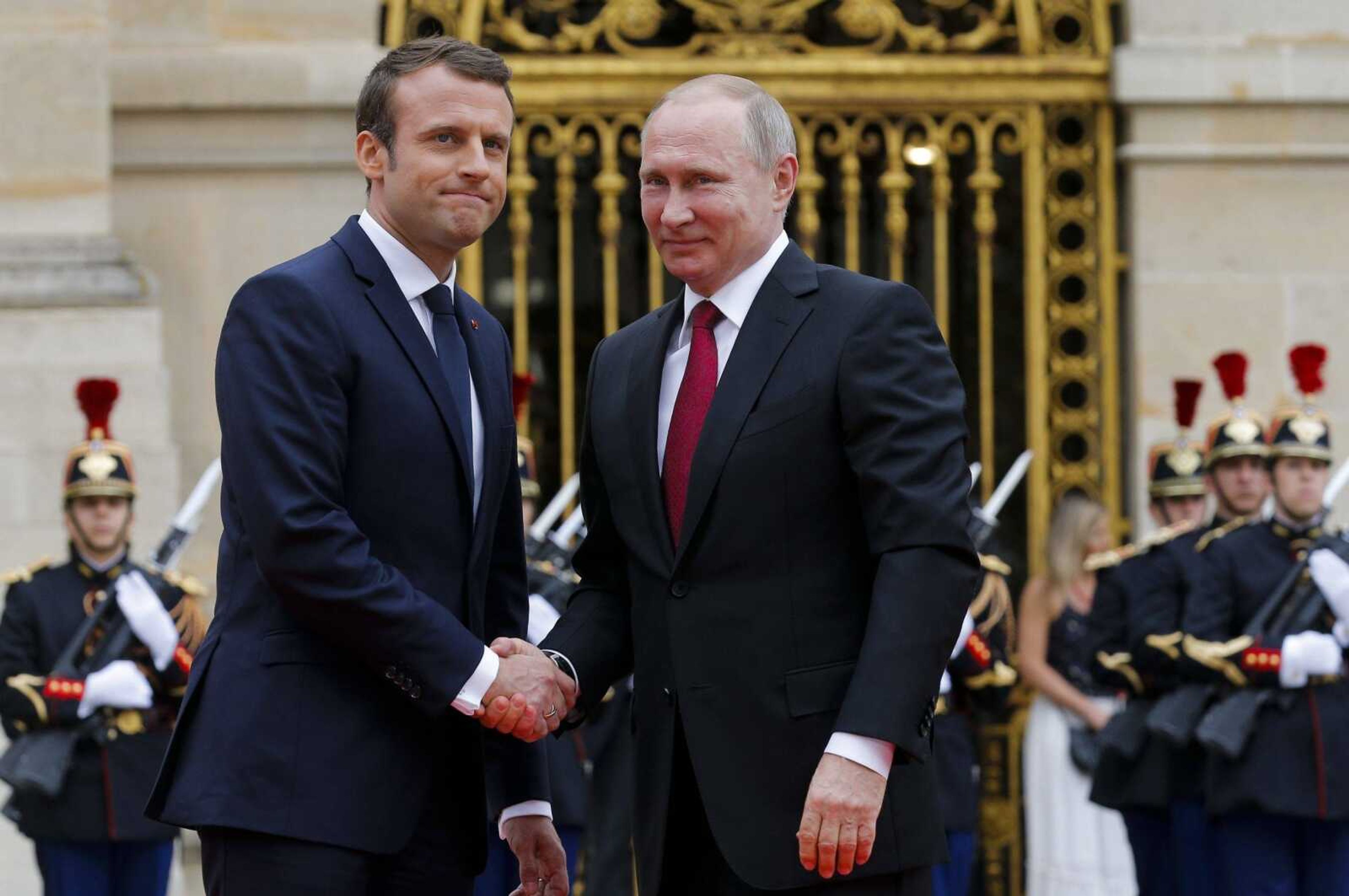 Russian President Vladimir Putin, right, is welcomed Monday by French President Emmanuel Macron at the Palace of Versailles near Paris.