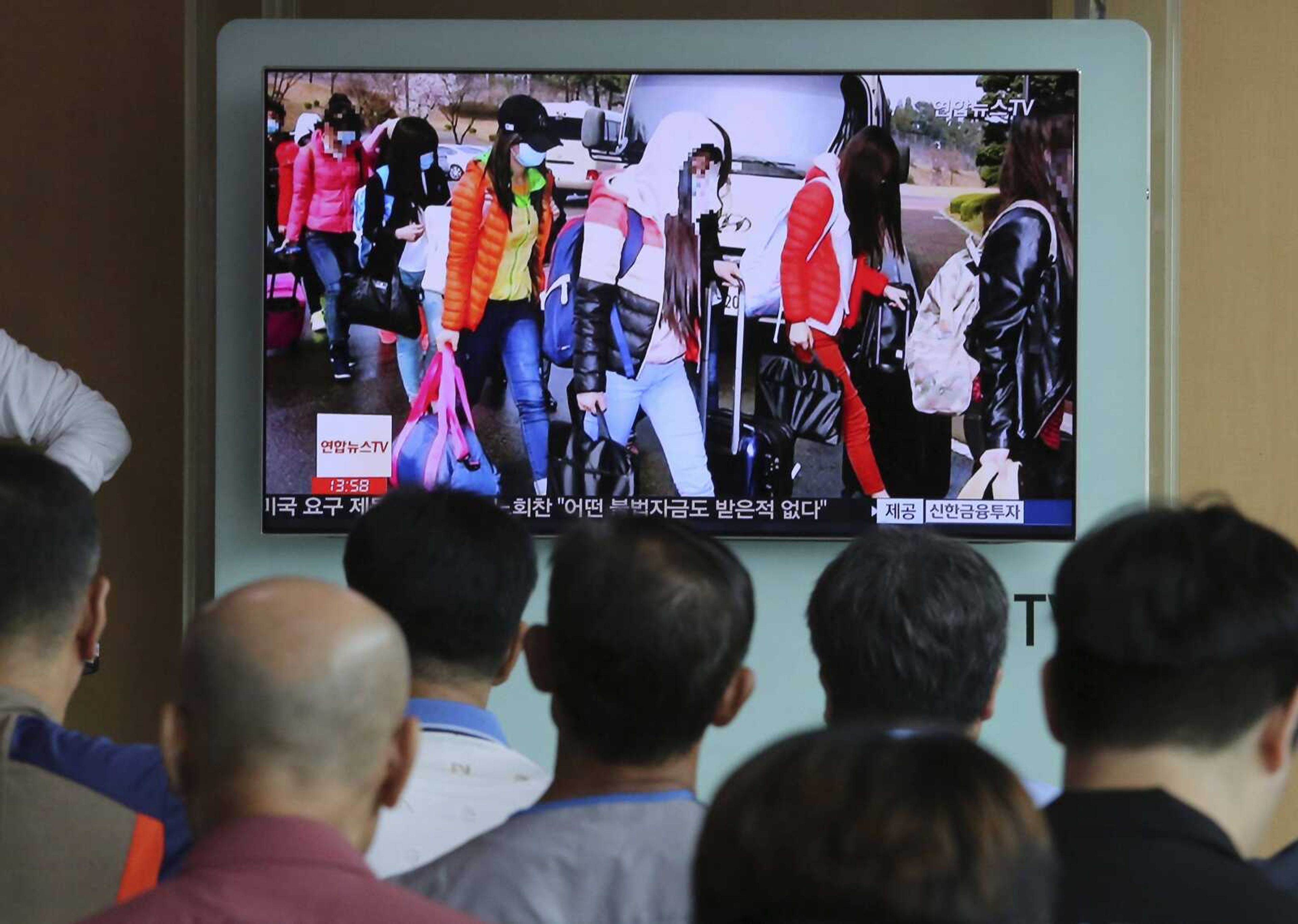 People watch a TV screen showing the 2016 arrival of a group of 12 female employees from a North Korean-run restaurant in China, during a news program Friday at Seoul Railway Station in Seoul, South Korea.