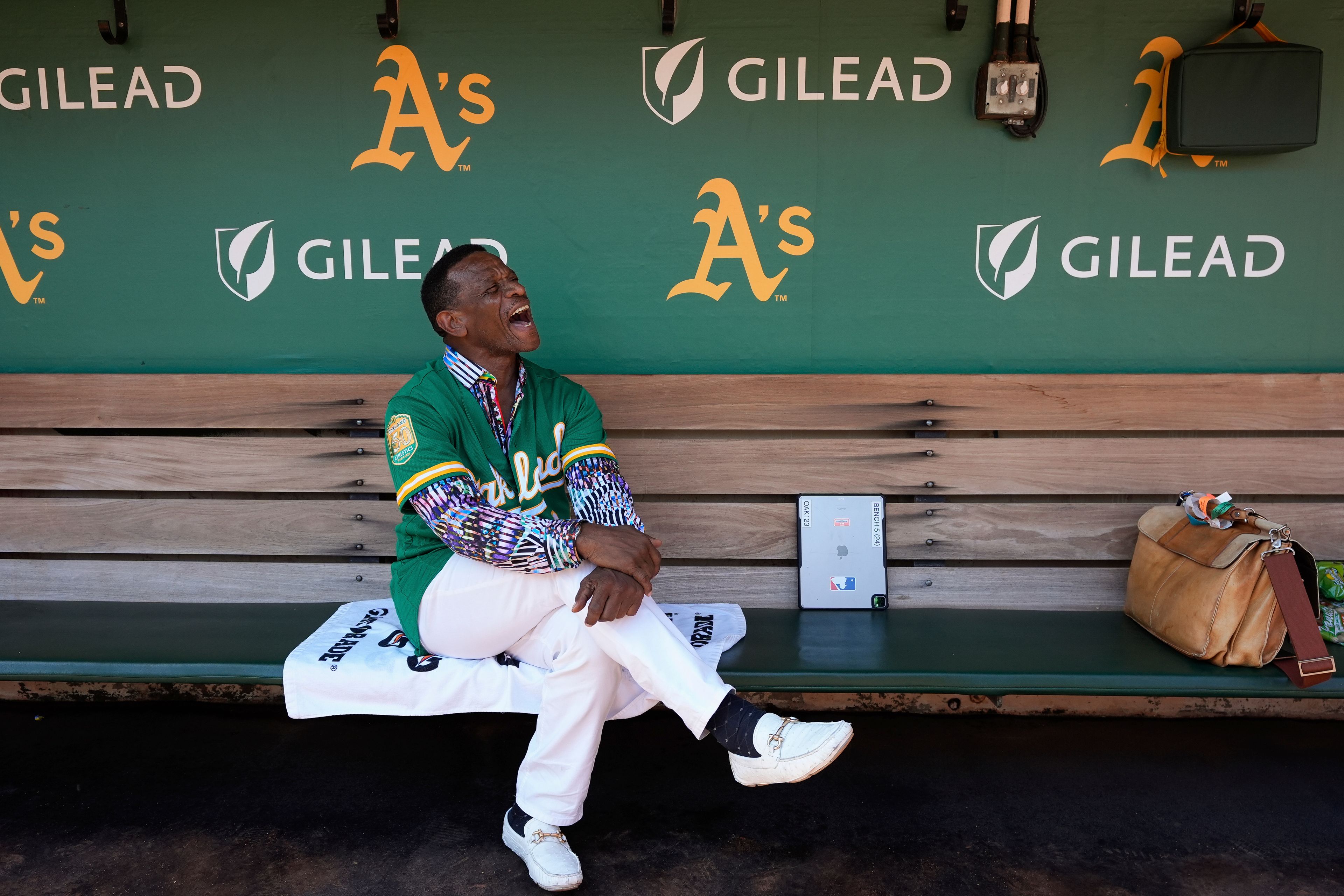 Former baseball player Rickey Henderson laughs as he sits in the dugout before a baseball game between the Oakland Athletics and the Texas Rangers, Thursday, Sept. 26, 2024, in Oakland, Calif. (AP Photo/Godofredo A. Vásquez)