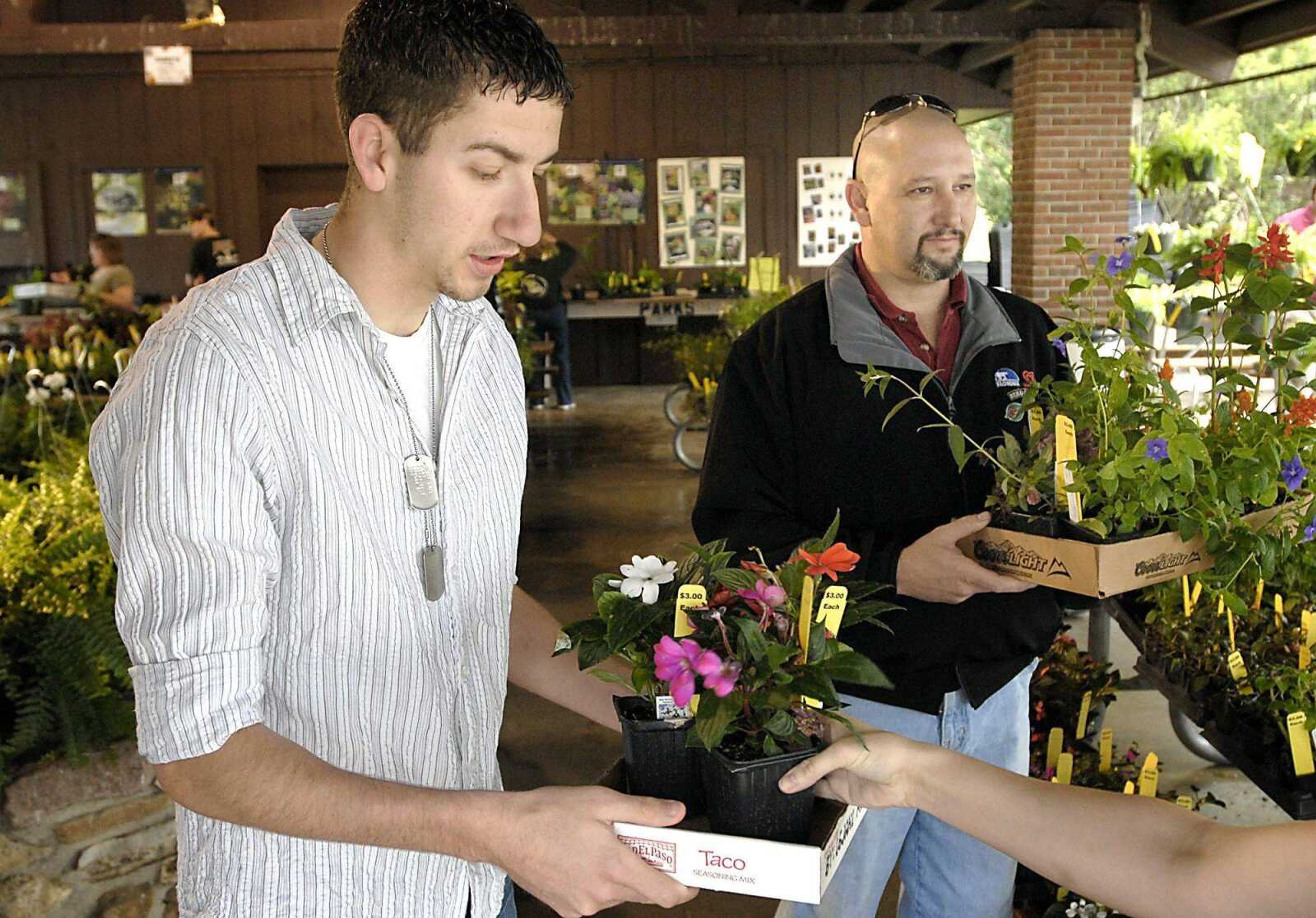 Brandon Bell, left, and Jerry Lewis carry selections for their first flower pot and experienced garden, respectively, April 18, during the Cape Master Gardeners sale at Arena Park.