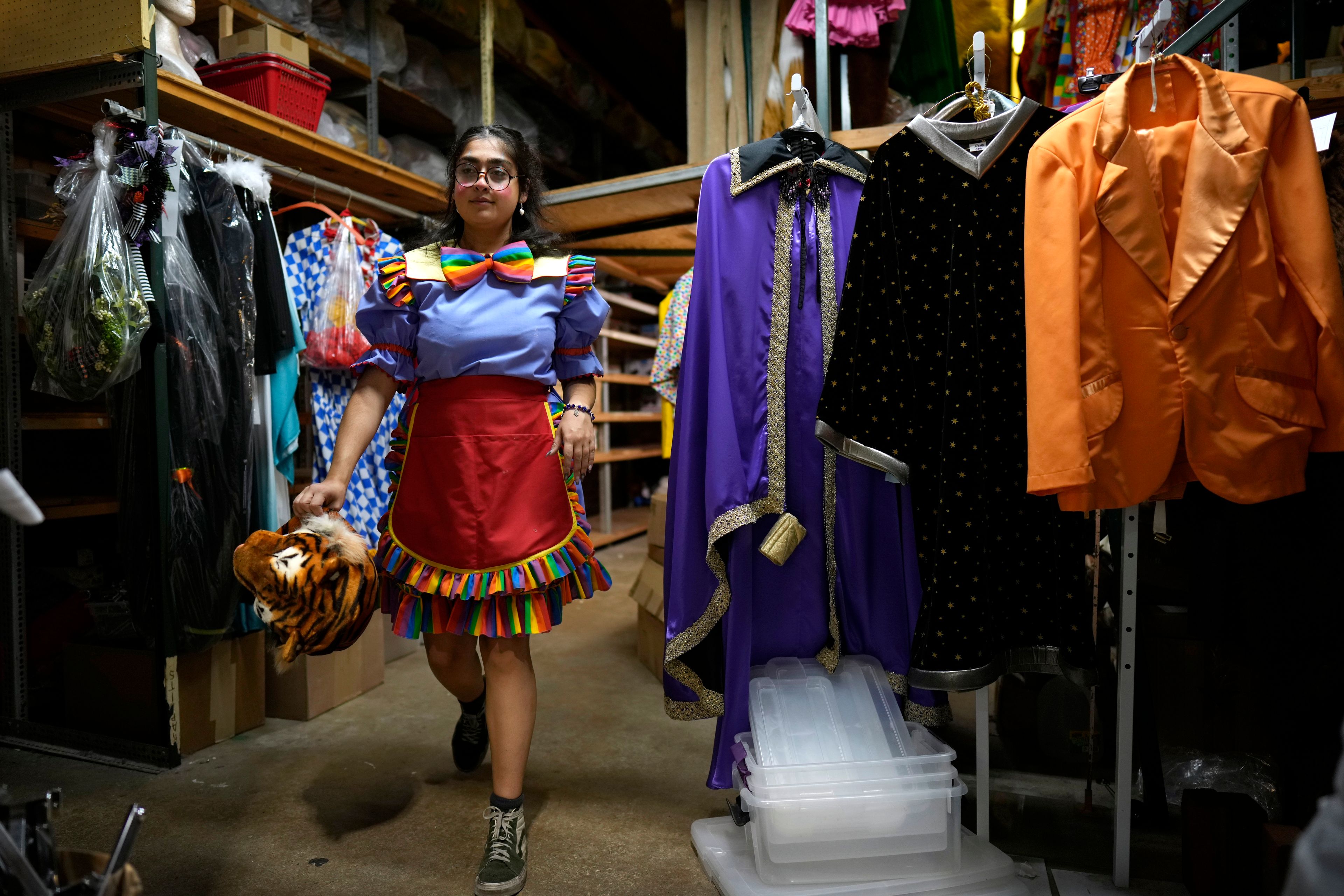 Hamida Mokhtar walks past costumes in the storeroom at The Theatrical Shop, Tuesday, Oct. 29, 2024, in West Des Moines, Iowa. (AP Photo/Charlie Neibergall)