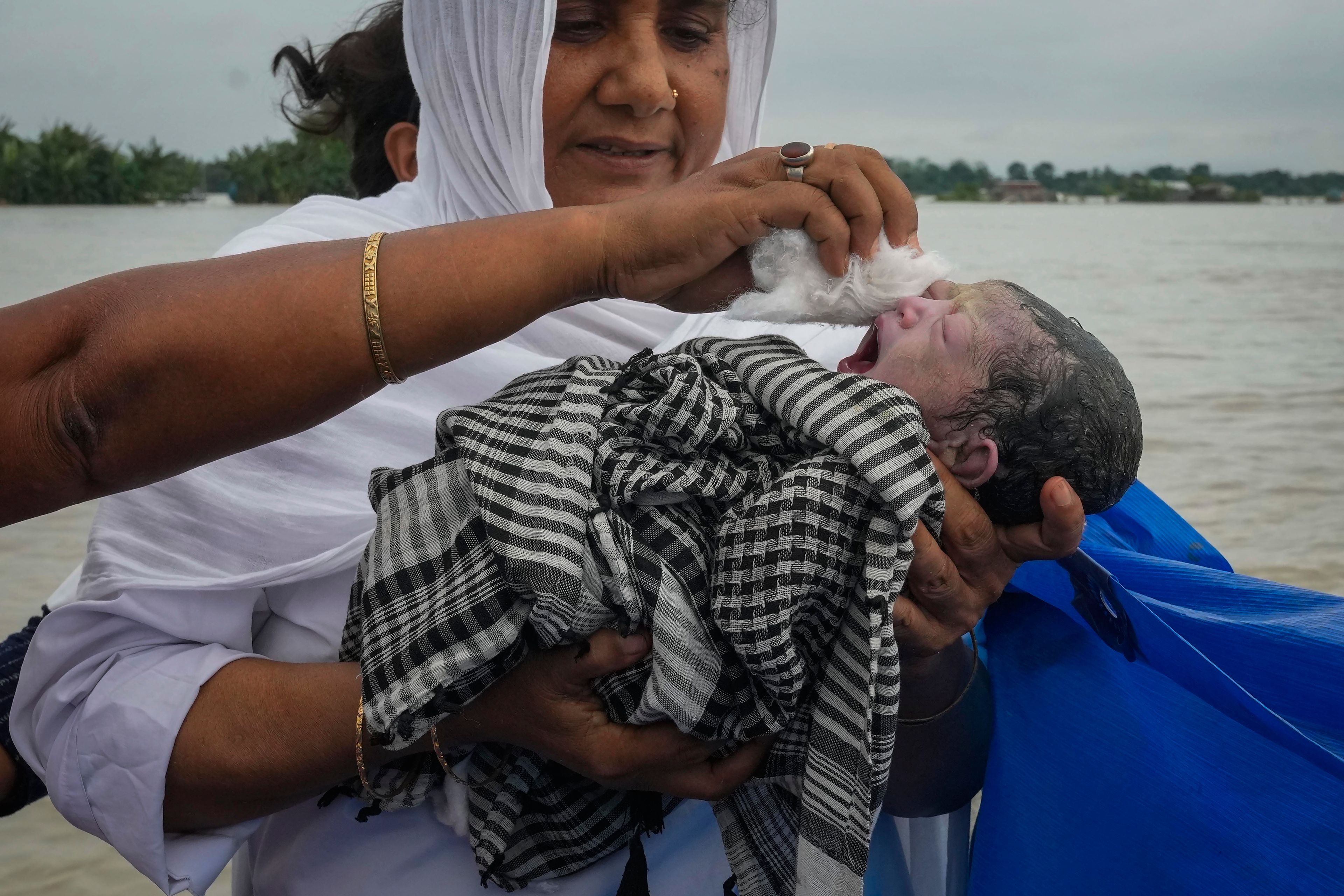 Midwife Diluwara Begum holds a newborn baby girl after helping deliver her on a boat on the River Brahmaputra, in the northeastern Indian state of Assam, on July 3, 2024. (AP Photo/Anupam Nath)