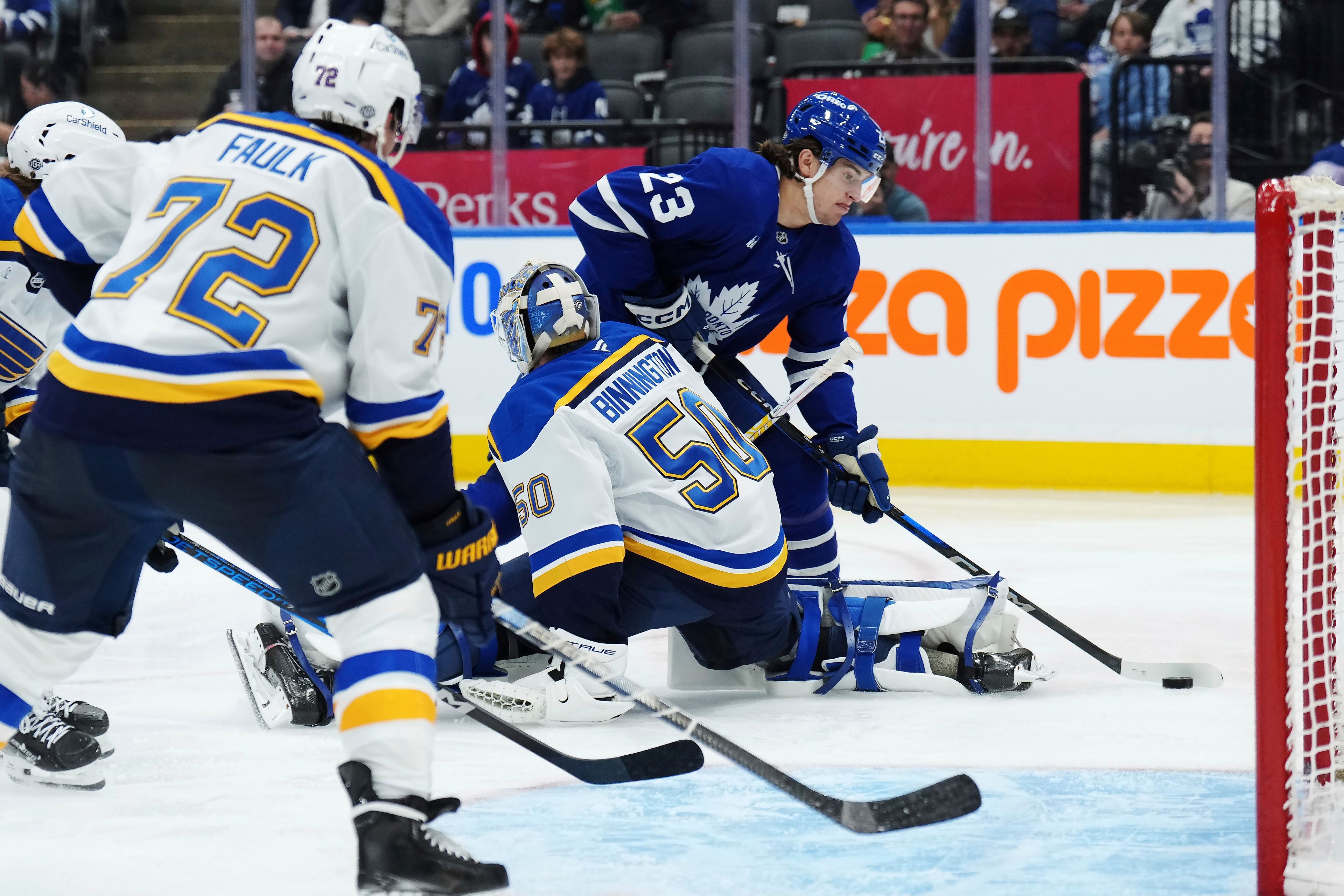 Toronto Maple Leafs forward Matthew Knies (23) tries to get around St. Louis Blues goaltender Jordan Binnington (50) during second-period NHL hockey game action in Toronto, Thursday, Oct. 24, 2024. (Nathan Denette/The Canadian Press via AP)