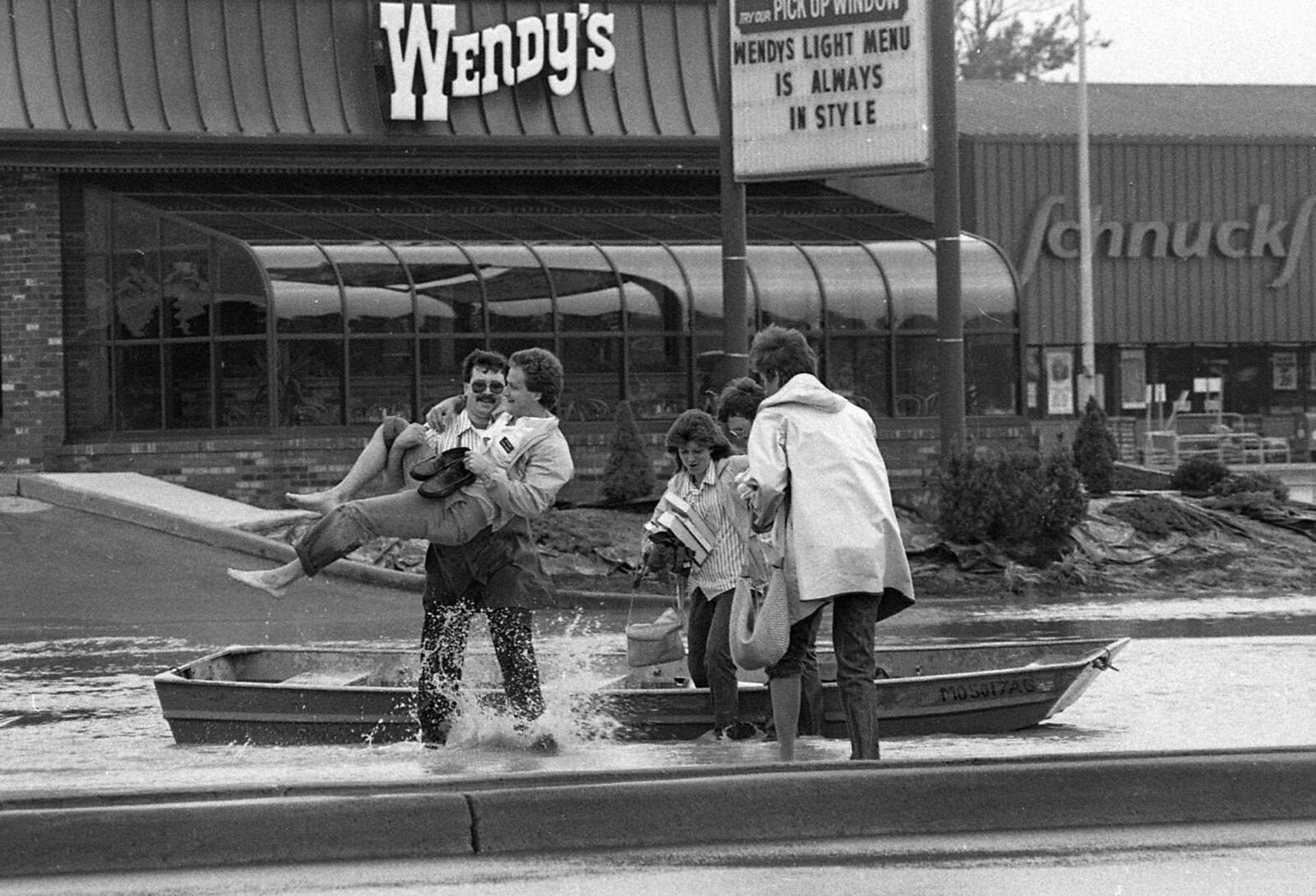 People get to work by boat on May 16, 1986 as floodwaters still cover Kingshighway. (Southeast Missourian)