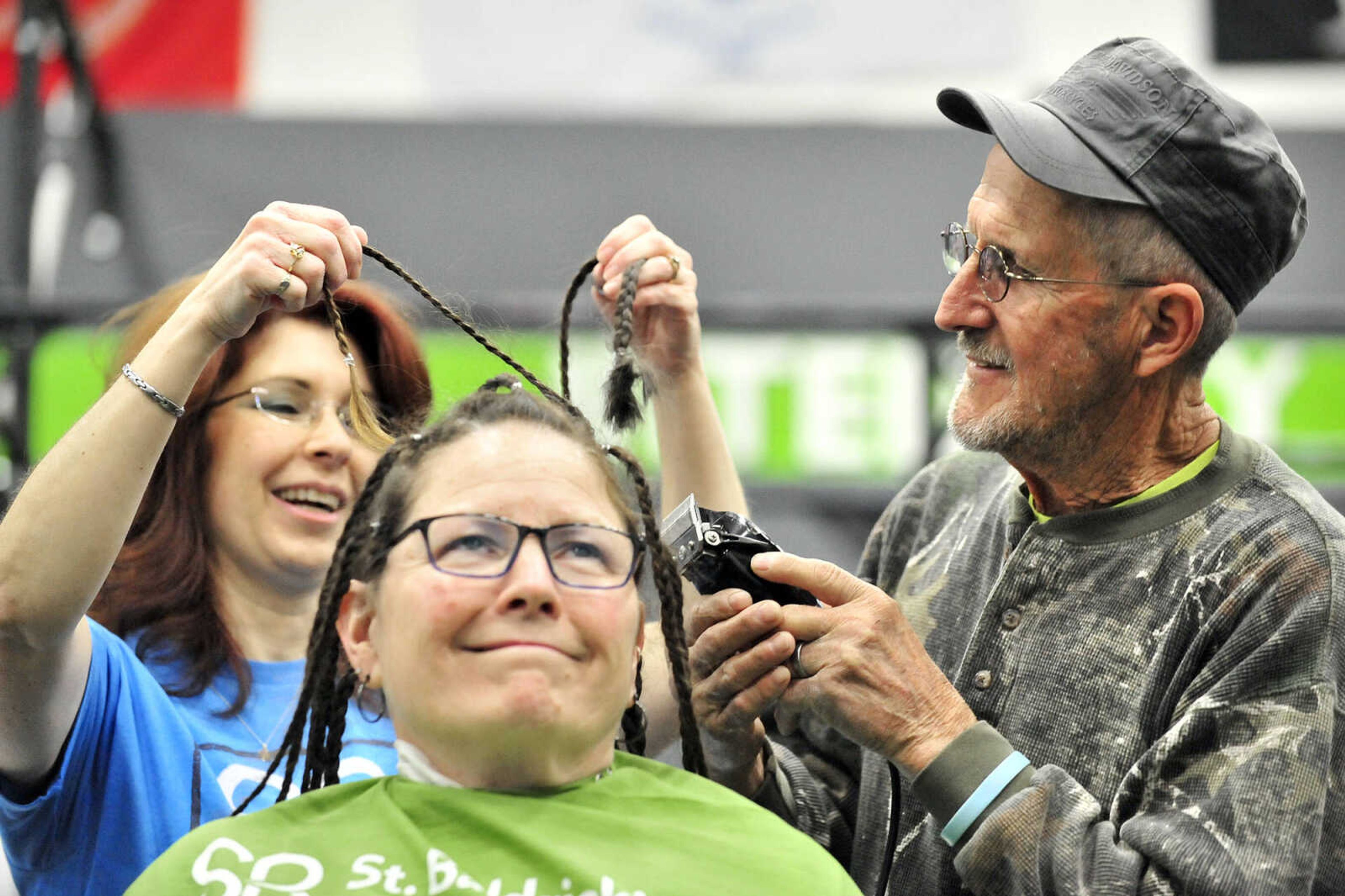 April Whiteside holds out some of Cathy Klaus' braids so Klaus' husband Kirby can shave them off on Saturday, March 4, 2017, during the St. Baldrick's Foundation fundraiser at Old Orchard CrossFit in Jackson.