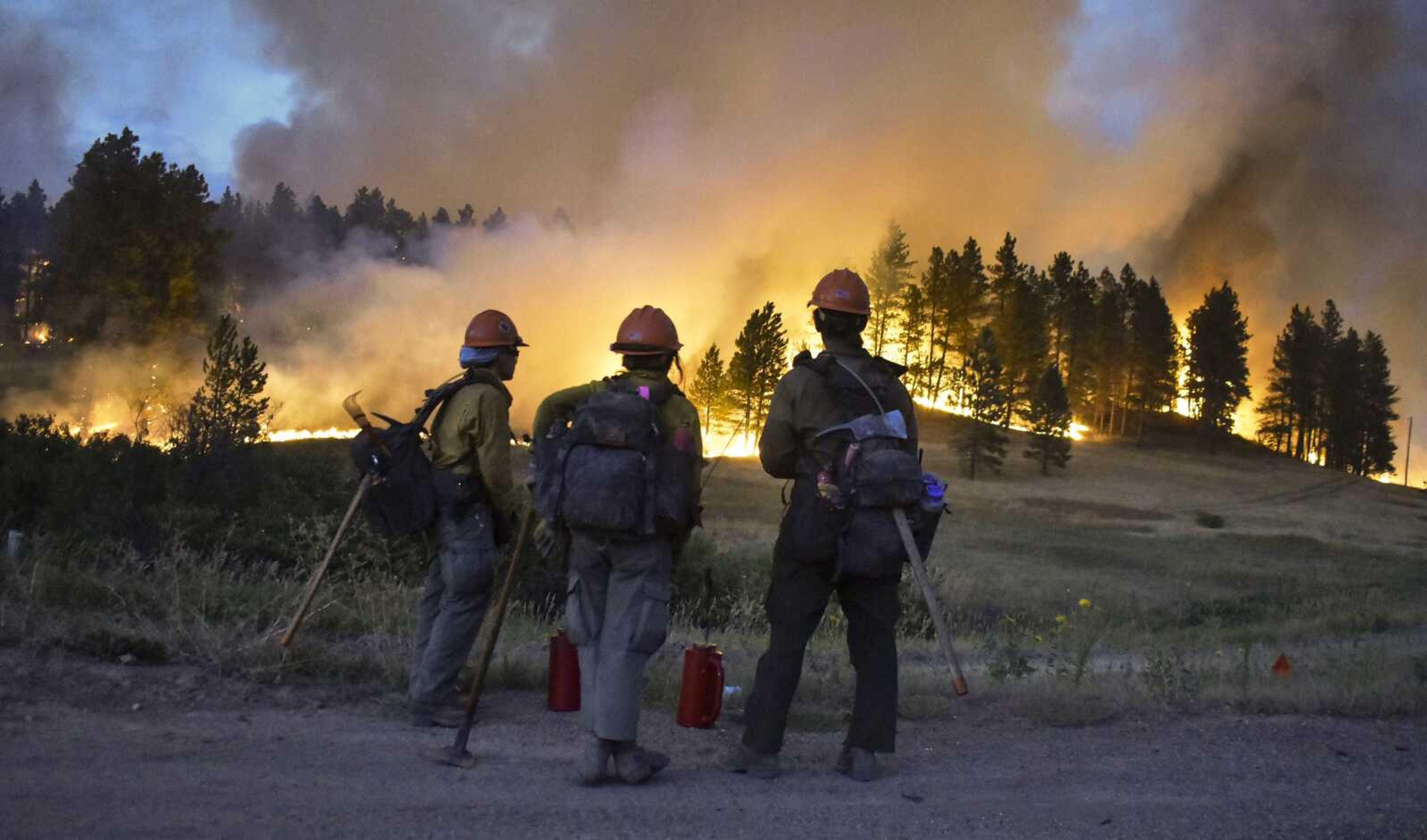 Firefighters watch a hillside burn on the Northern Cheyenne Indian Reservation on Wednesday near Lame Deer, Montana. The Richard Spring fire was threatening hundreds of homes as it burned across the reservation.