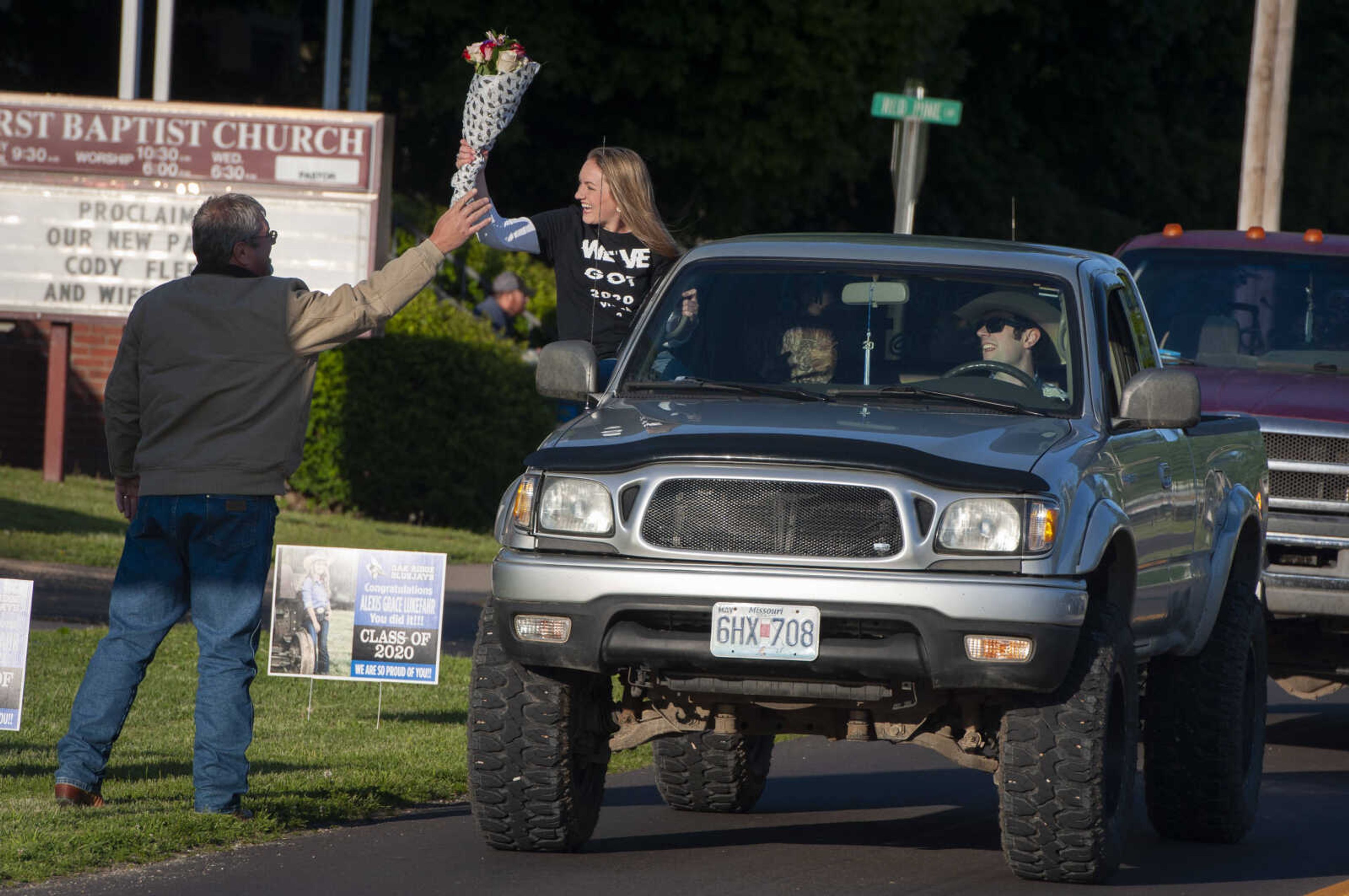 On the day her high school graduation was supposed to be held, Oak Ridge High School senior Alexis Lukefahr receives flowers from her father Curtis Lukefahr as her brother Lane Lukefahr drives her in a parade for the school's seniors Friday, May 8, 2020, in Oak Ridge. The senior parade made its way from Cape County Cowboy Church near Interstate 55 and through the community to Oak Ridge High School. Adrian Eftink, superintendent of the Oak Ridge R-VI School District, said a group of parents who wanted to do something for the seniors approached the school district about the parade. "It just makes you proud of the community," Eftink said. "Being an administrator and a member of the staff here, to see the community support our students, it just gives you a good warm feeling [and] pride in the Oak Ridge community."