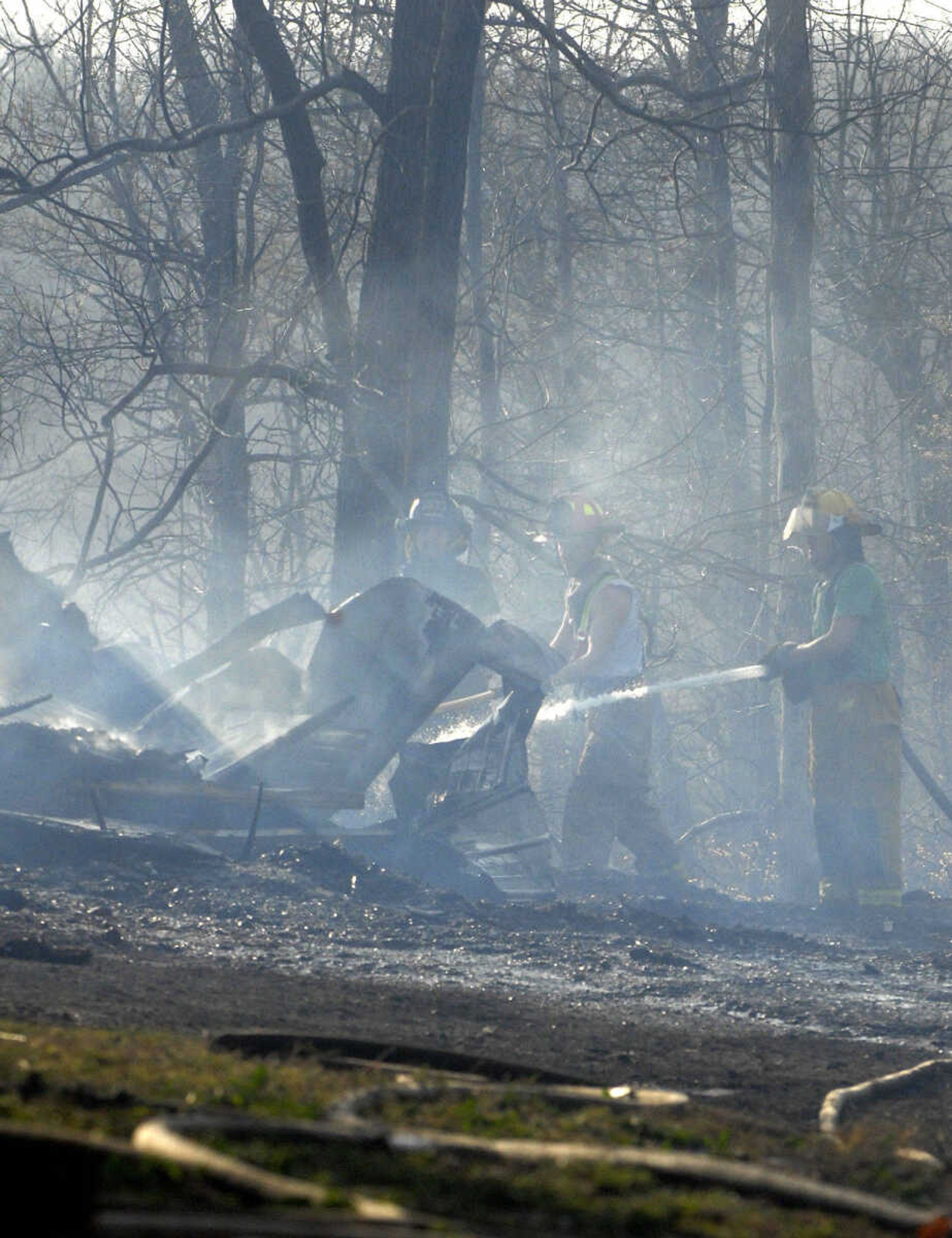 LAURA SIMON~lsimon@semissourian.com
Fire crews extinguish fire on the rubble of a shed that burned to the ground during a natural cover fire off of Cissus Lane in rural Cape Girardeau County Sunday, April 3, 2011. Firefighters from Cape Girardeau, Perry, Scott, and Bollinger Counties contained the blaze that ravaged 50 acres of land.