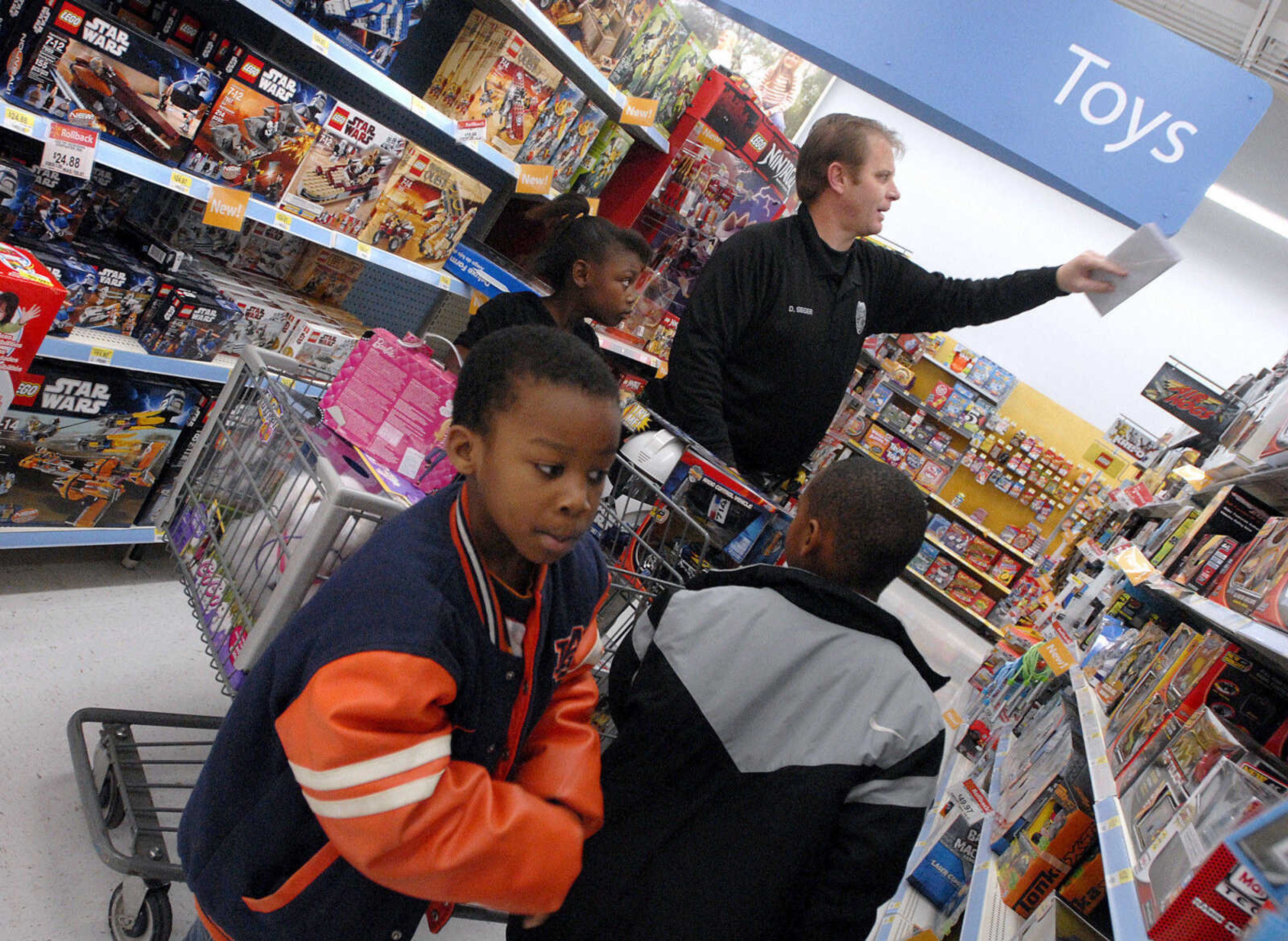 LAURA SIMON ~ lsimon@semissourian.com
Cape Girardeau school resource officer Dan Seger helps Evian Baker, Da 'Saan Baker, left, and Kijaun French pick out toys Tuesday morning, Dec. 6, 2011 at Walmart in Cape Girardeau. The children were just three out of around 100 children that got to Shop with a Hero Tuesday morning. This is the 20th year that Walmart has held the Christmas shopping event that allows children to shop with donated money for toys, clothing or any item of their choice within the amount raised. This year each child received around $85 to spend with the help of local police officers, firefighters and first responders.