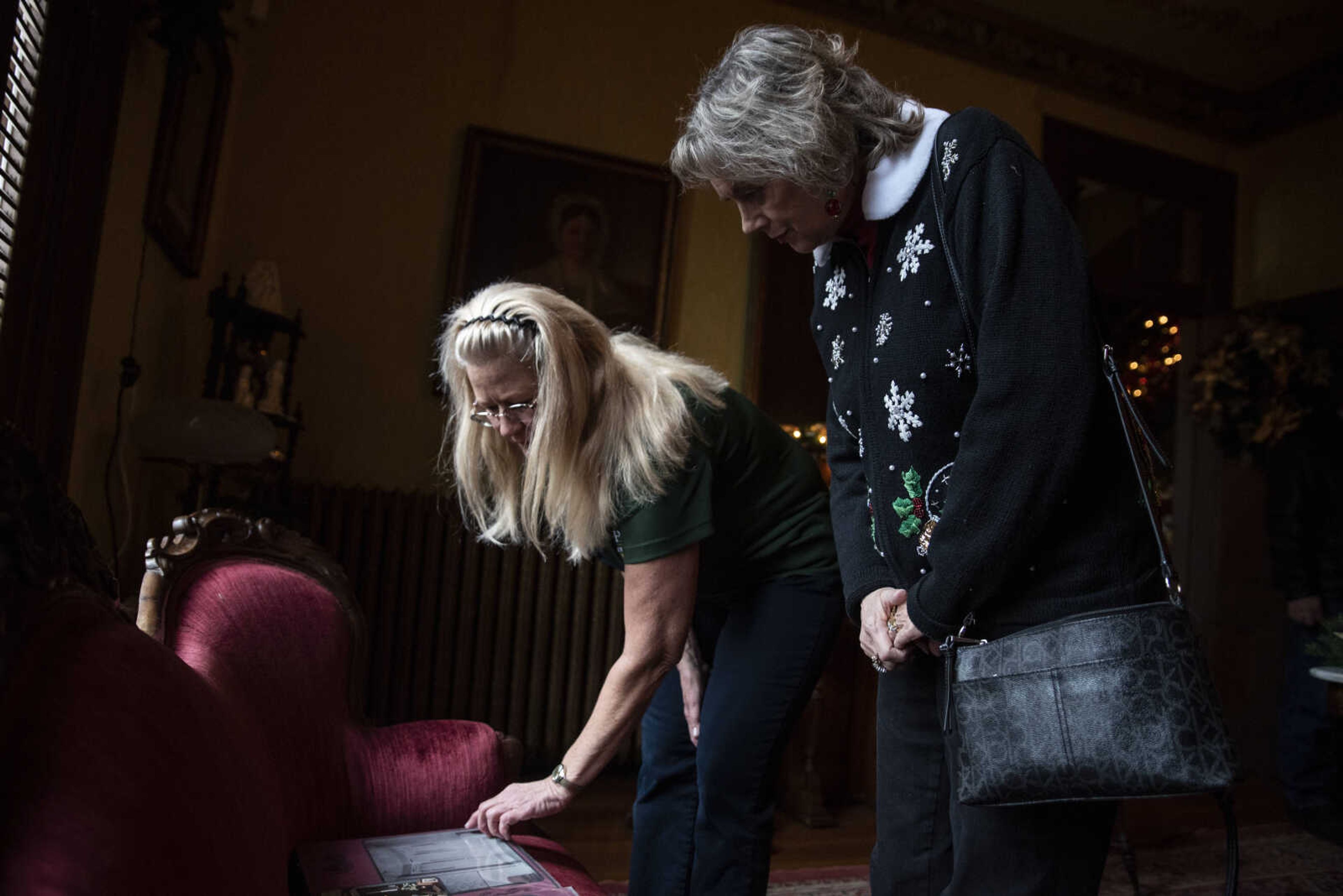 Sue Morrow, right, looks at a family photo album with volunteer Sue Morrow, left, during the first Christmas tour of the Glenn House Sunday, Dec. 23, 2018, in Cape Girardeau.