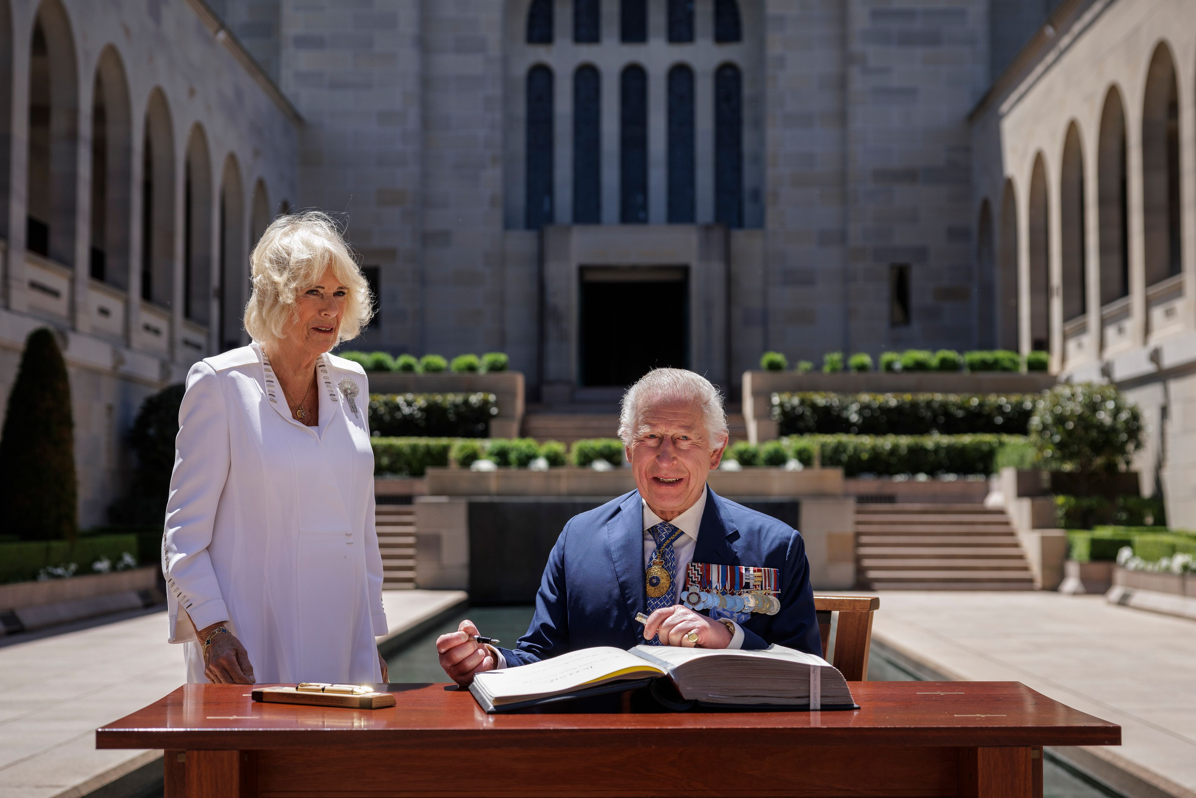 Britain's King Charles III signs a visitor's book as Queen Camilla stands next to him at the Australian War Memorial in Canberra, Australia, Monday, Oct. 21, 2024. (Brook Mitchell/Pool Photo via AP)