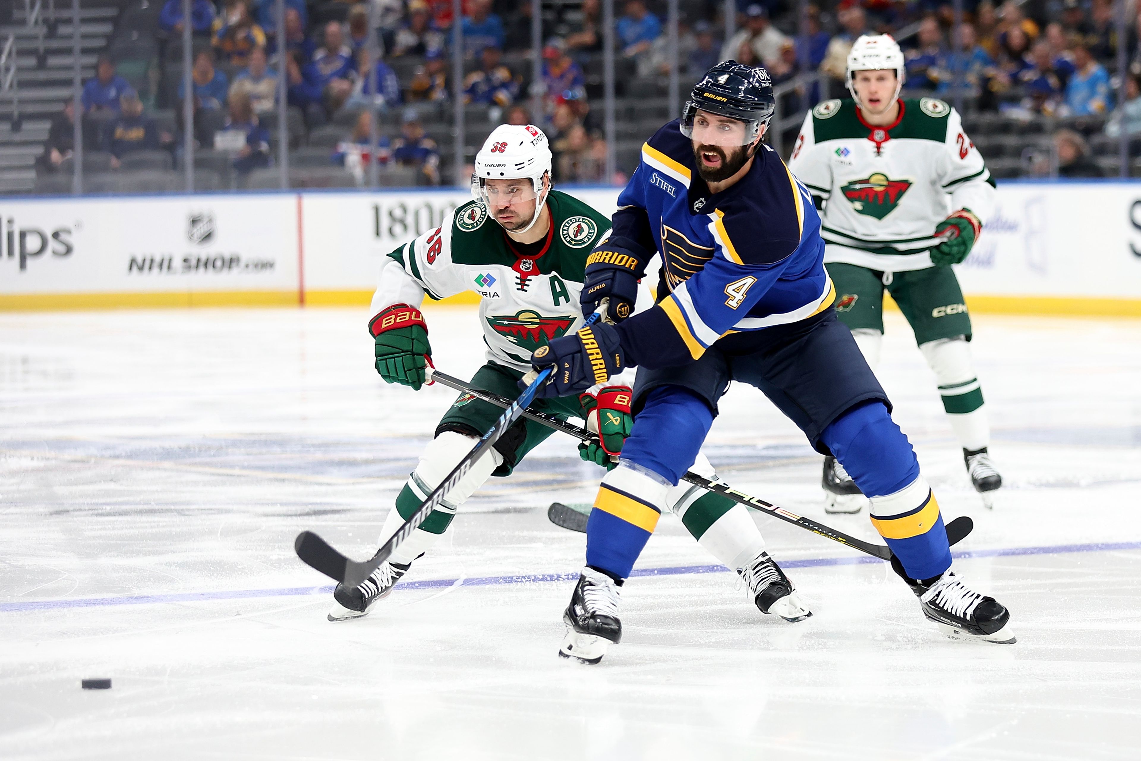 St. Louis Blues' Nick Leddy (4) passes the puck while under pressure from Minnesota Wild's Mats Zuccarello (36) during the second period of an NHL hockey game Tuesday, October 15, 2024, in St. Louis. (AP Photo/Scott Kane)