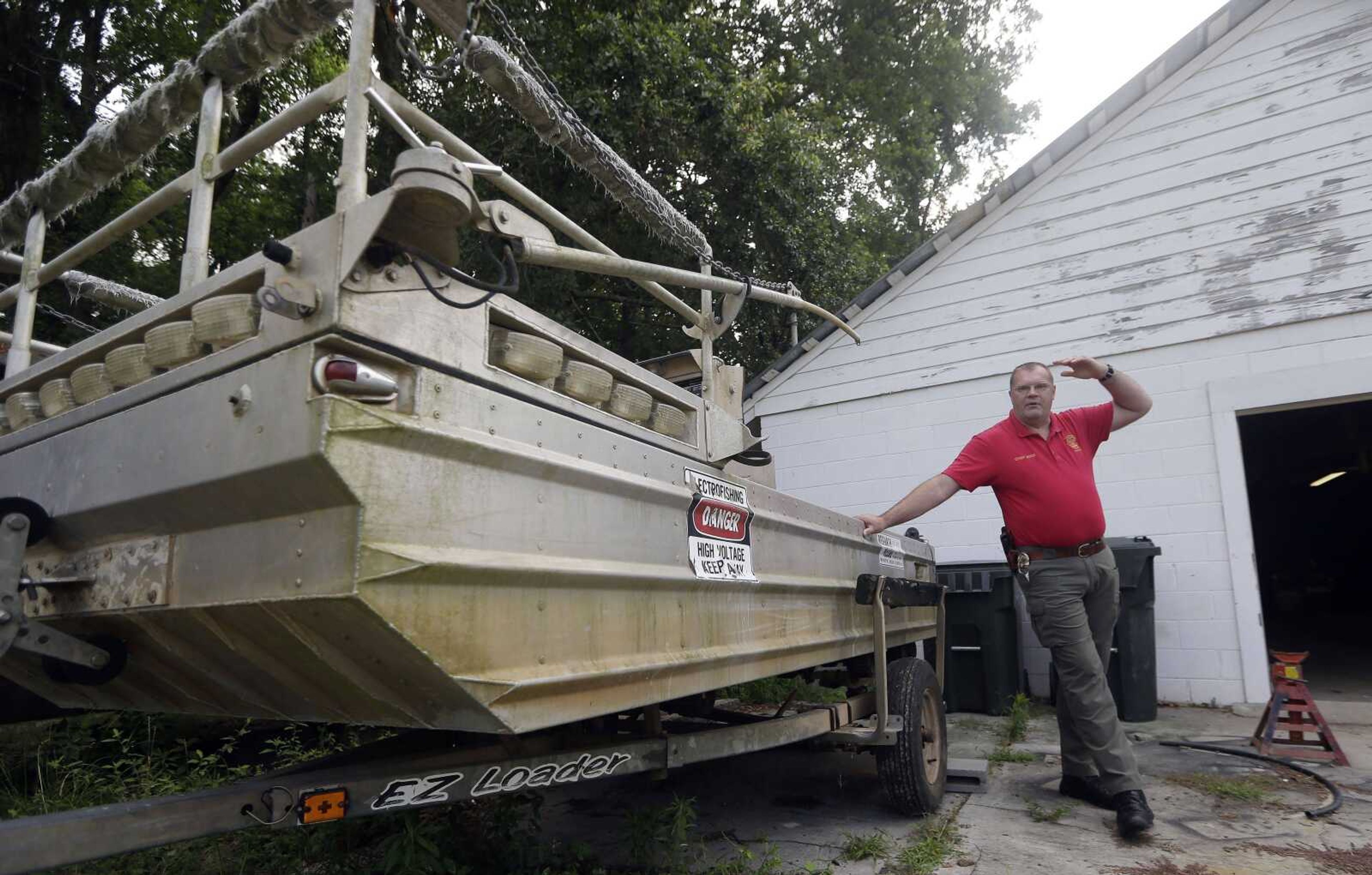 Morven, Ga., Police Chief Lynwood Yates stands next to a government surplus boat. The chief has acquired three boats, scuba gear, rescue rafts and two dozen life preservers. The town&#8217;s deepest body of water is an ankle-deep creek. (John Bazemore ~ Associated Press)