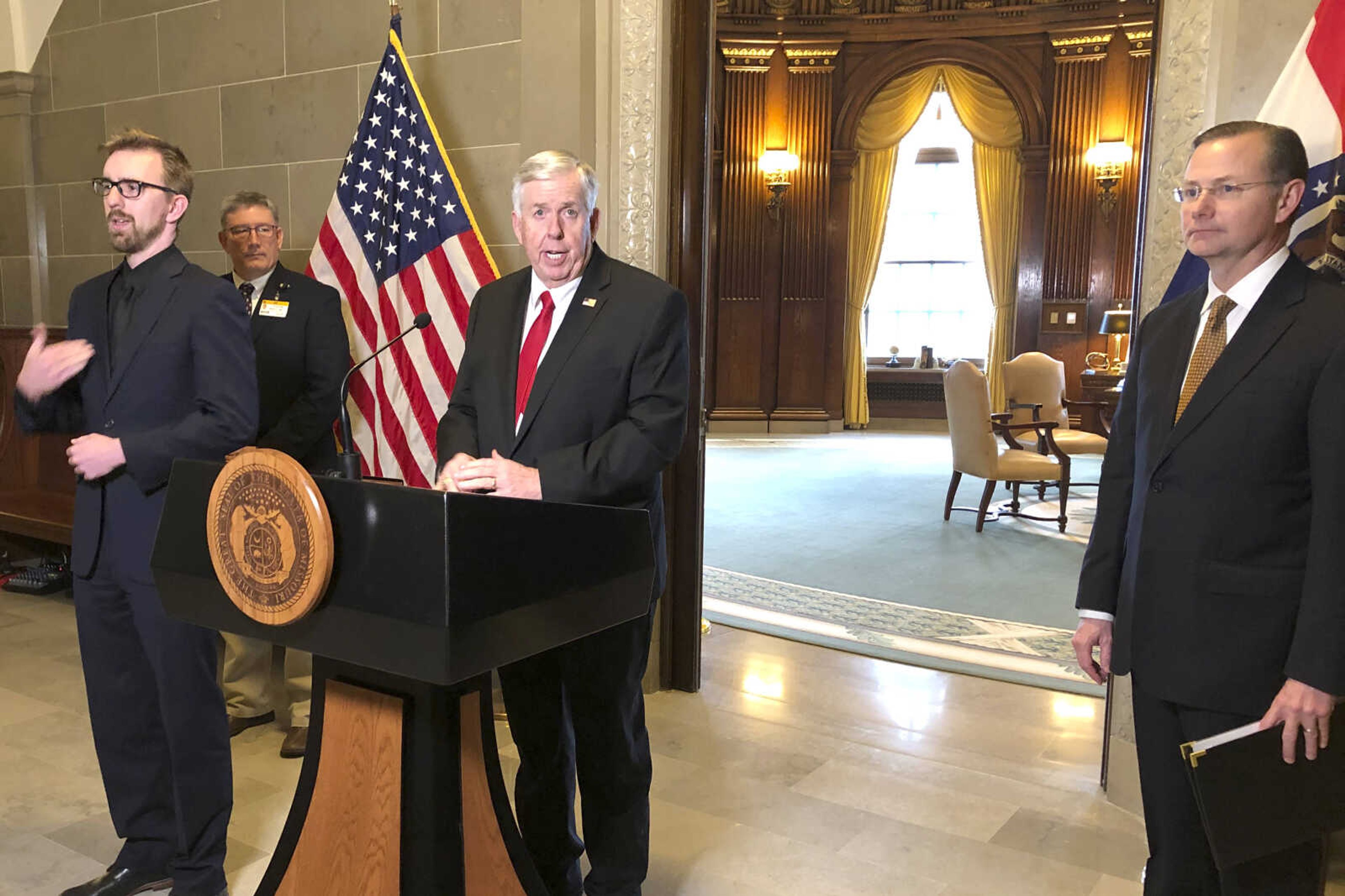 Missouri Gov. Mike Parson, center, announces that the state experienced its first death from the coronavirus, Wednesday, March 18, 2020, during a news conference in Jefferson City, Mo,  Columbia Mayor Brian Treece is at right. (AP Photo/David A. Lieb)