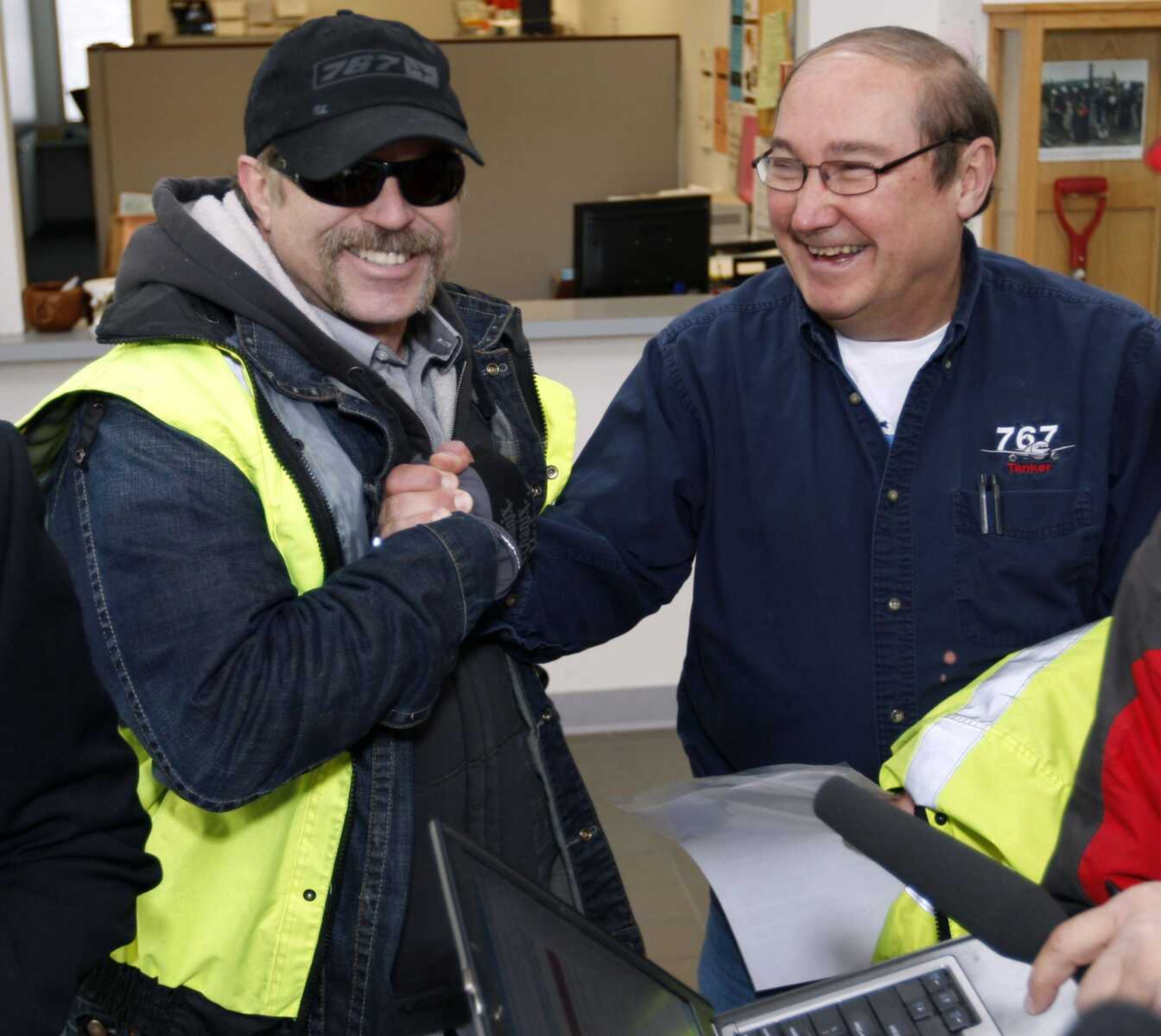 Boeing 767 workers Dale Flinn, left, and David Mellenbach clasp hands Thursday in Everett, Wash., at the news that the U.S. Air Force awarded a $35 billion contract to Boeing Co. to build the next generation of air refueling planes. (Kevin P. Casey ~ Associated Press)