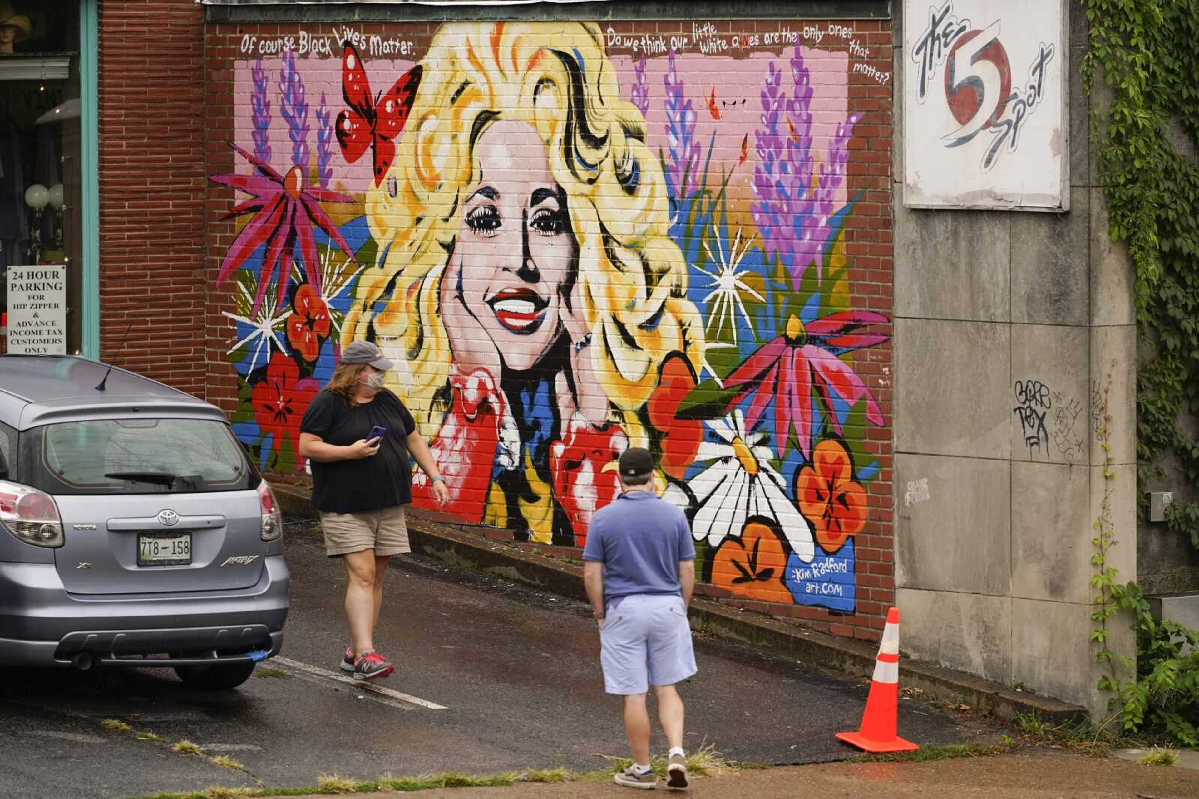 People look at a mural of Dolly Parton outside The 5 Spot music club Friday in Nashville, Tennessee. Artist Kim Radford said Dolly fans from around the world have contacted her about the mural, which contains a quote from Parton about her support for the Black Lives Matter movement.