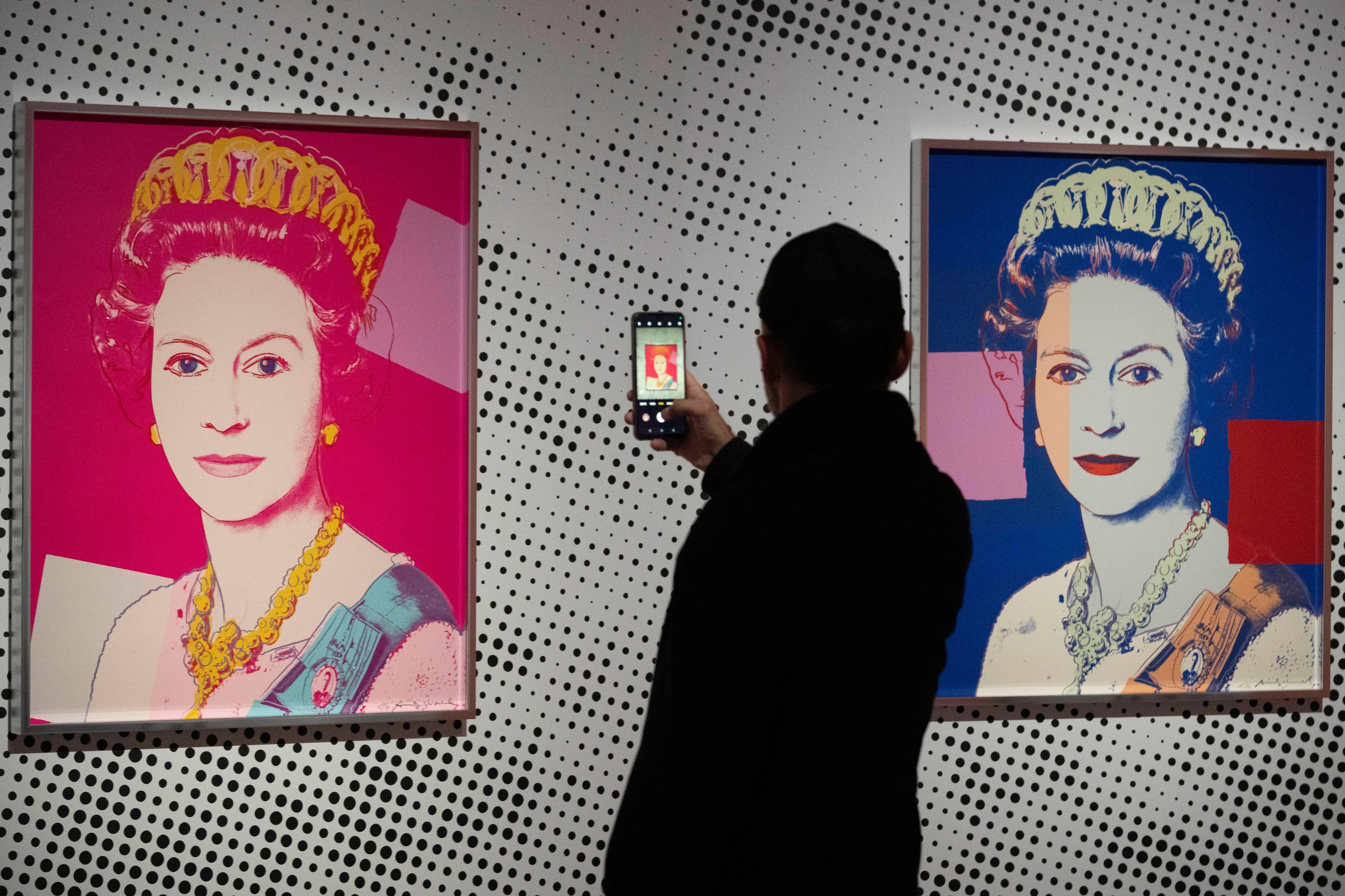 A man takes an image of a screen print depicting Queen Elizabeth II, one in a series of sixteen prints of four queens titled Reigning Queens, 1985, by Andy Warhol at museum Paleis Het Loo in Apeldoorn, Netherlands, Wednesday, Oct. 9, 2024, similar to a Warhol work stolen from a gallery in Oisterwijk, Netherlands, early Friday, Nov. 1, 2024. (AP Photo/Peter Dejong)