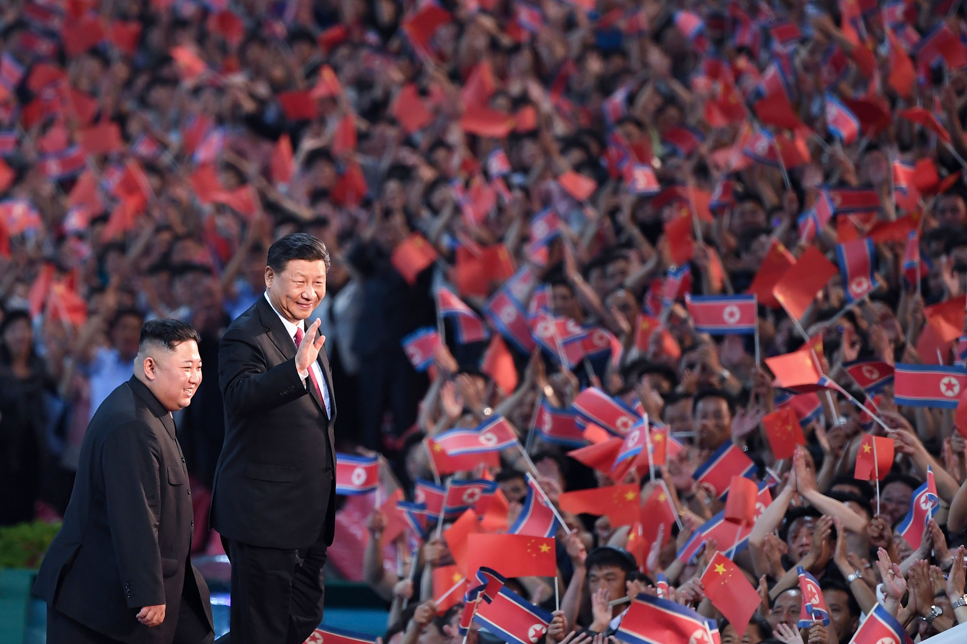 FILE - In this photo released by China's Xinhua News Agency, spectators wave Chinese and North Korean flags as North Korean leader Kim Jong Un, left, and visiting Chinese President Xi Jinping attend a mass gymnastic performance at the May Day Stadium in Pyongyang, North Korea, on June 20, 2019. (Yan Yan/Xinhua via AP, File)