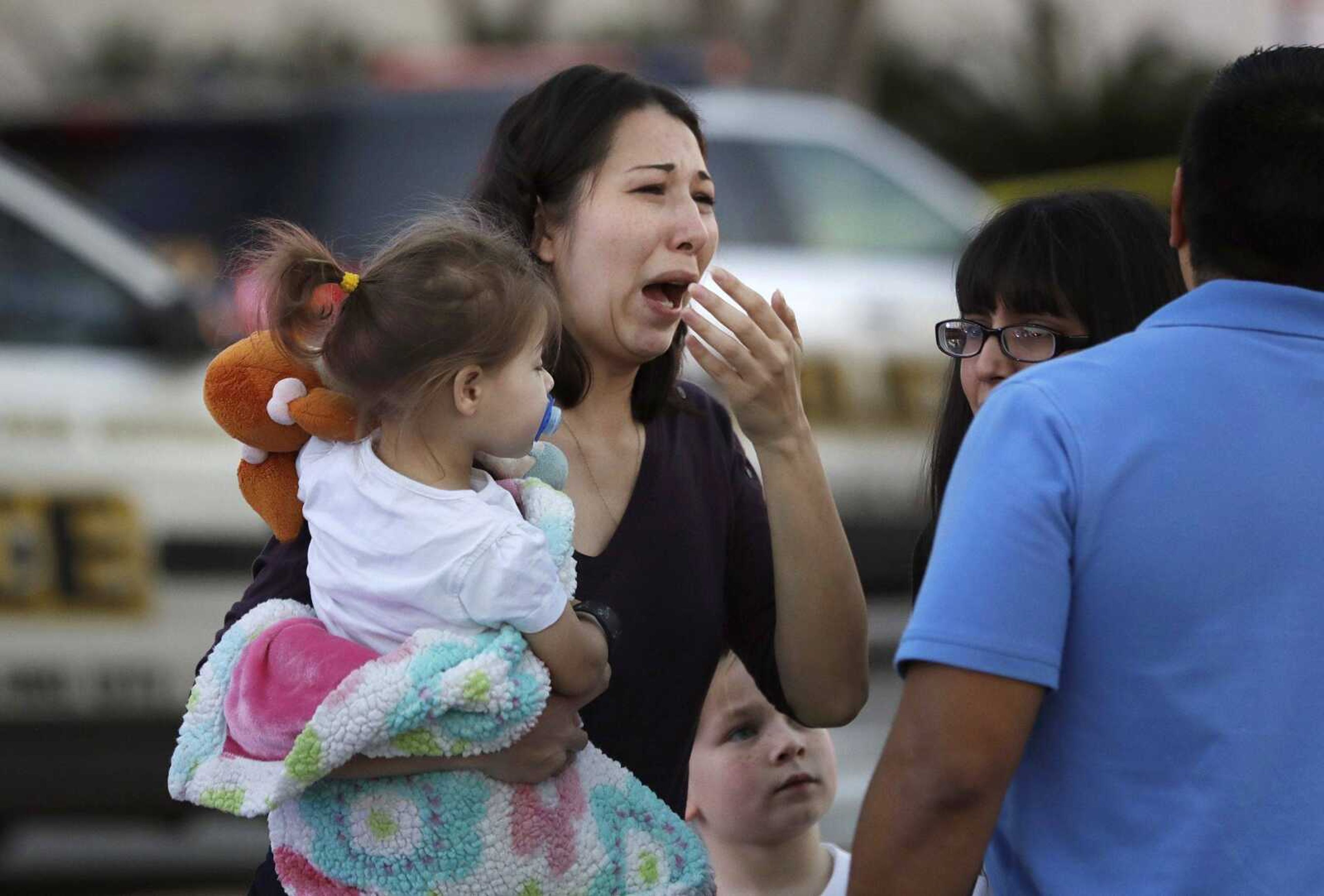 A woman holds her child after San Antonio police helped her and other shoppers exit the Rolling Oaks Mall on Sunday after a deadly shooting.