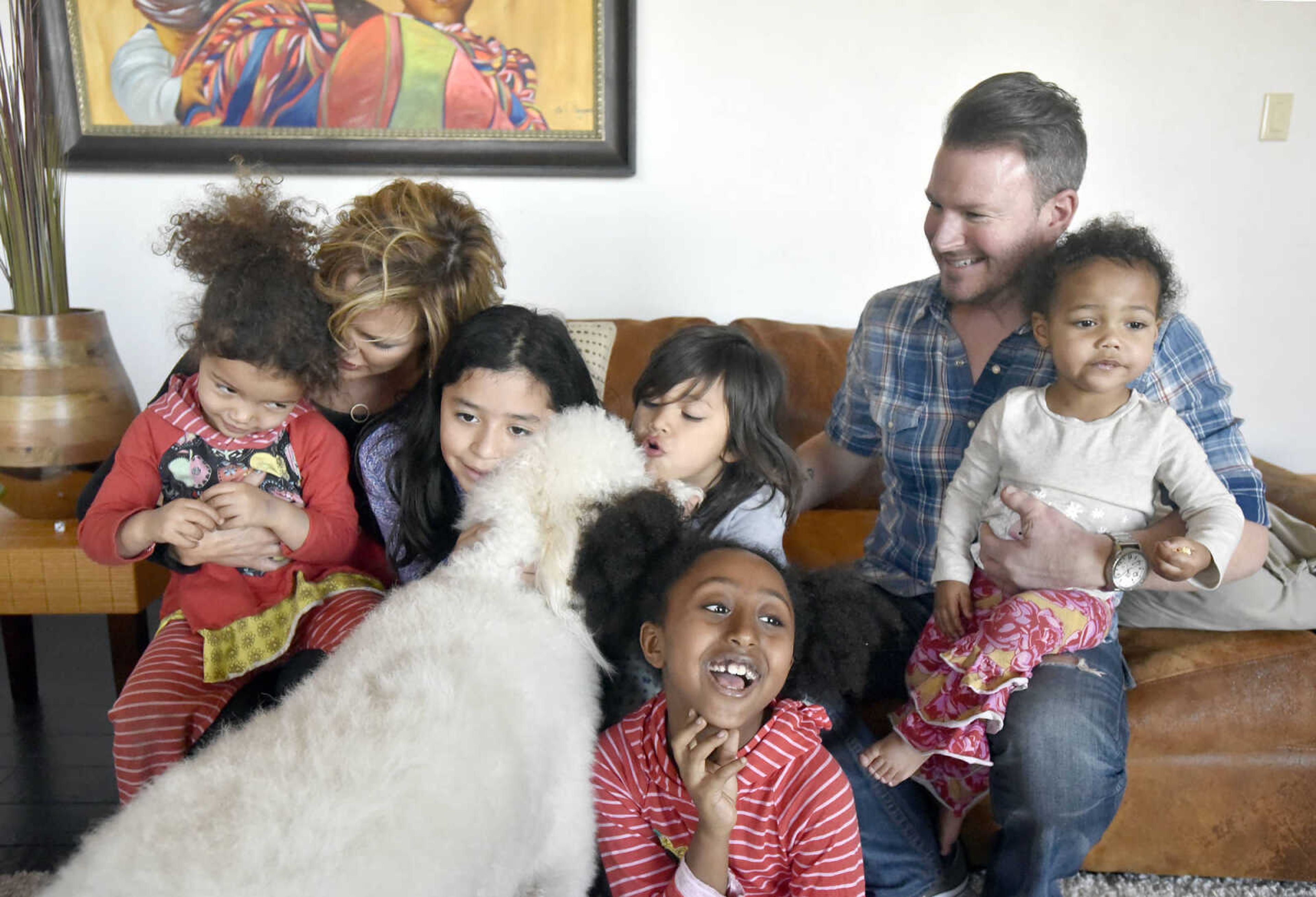 Pictured from left to right, Dolly, 3, Chantelle, Bianca, 10, Solie, 8, Ari, 5, Eric and Lennyx Becking, 1, group together for a family photo with their dog Marley on Saturday, Jan. 28, 2017, at the Becking's Cape Girardeau home.