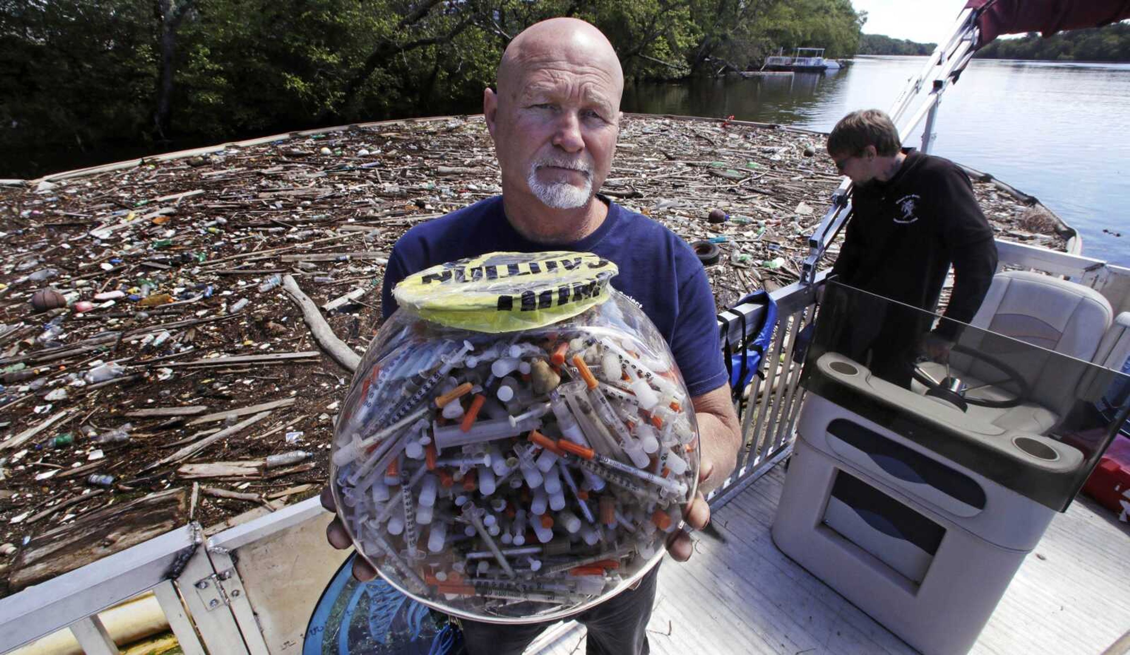 Activist Rocky Morrison of the "Clean River Project" holds up a fish bowl filled with hypodermic needles that were recovered during 2016 on the Merrimack River in Methuen, Massachusetts.