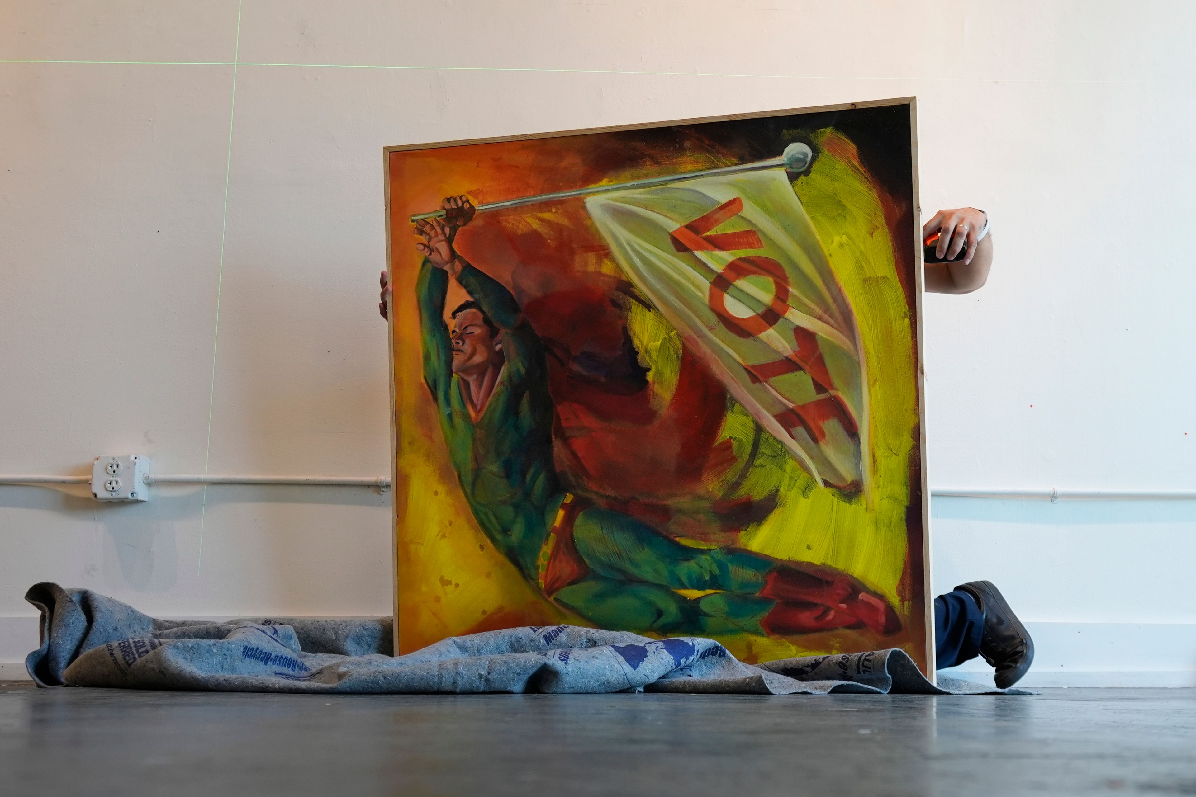 Artist David Alcantar prepares to hang a painting from his "Superman Project" for an upcoming show in San Antonio, Tuesday, Oct. 1, 2024. (AP Photo/Eric Gay)