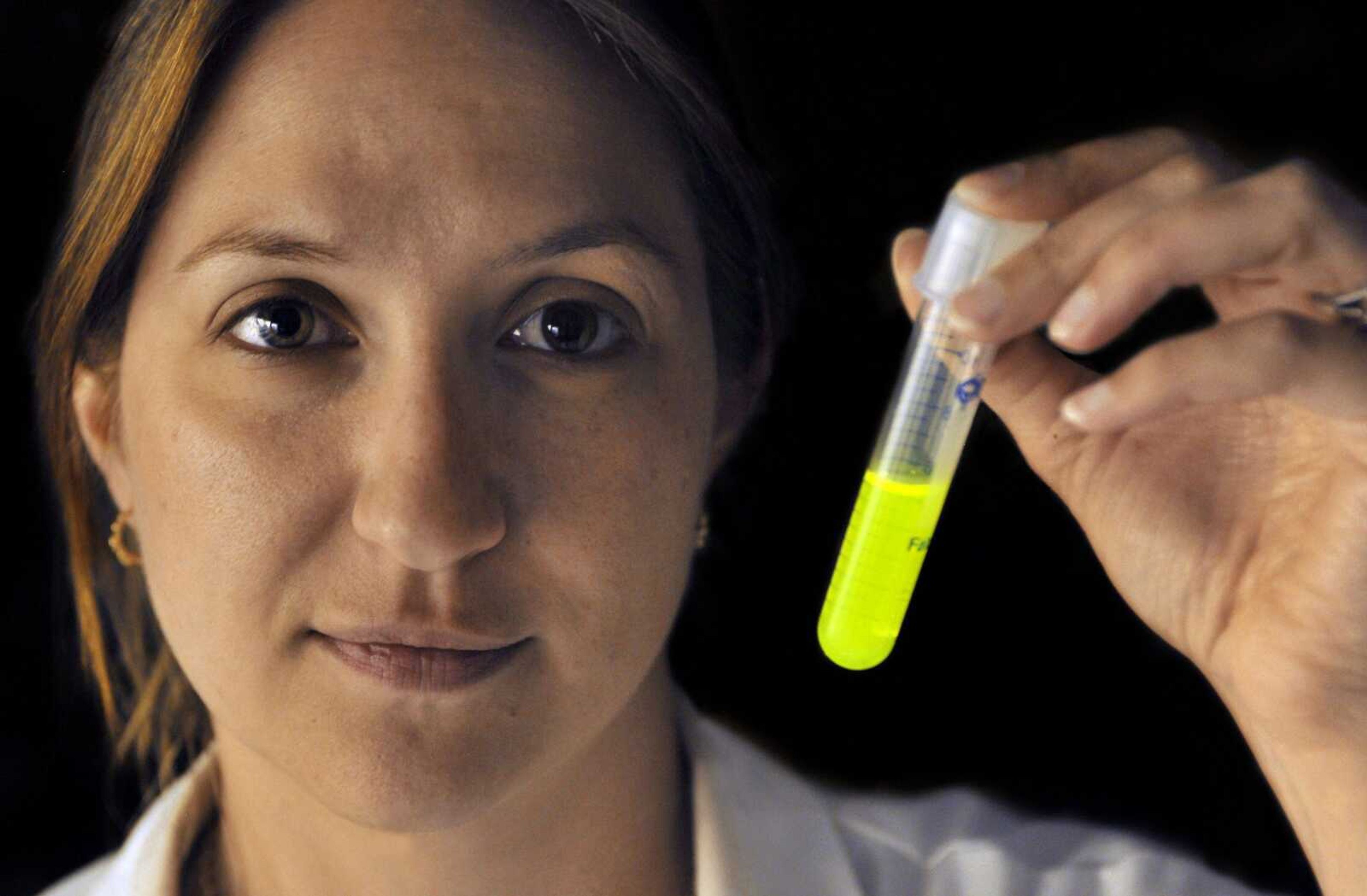 Research technician Danielle Fontaine holds a test tube glowing with bioluminescent protein Aug. 27. The protein is derived from fireflies at a laboratory at Connecticut College in New London, Conn. (Jessica Hill ~ Associated Press)