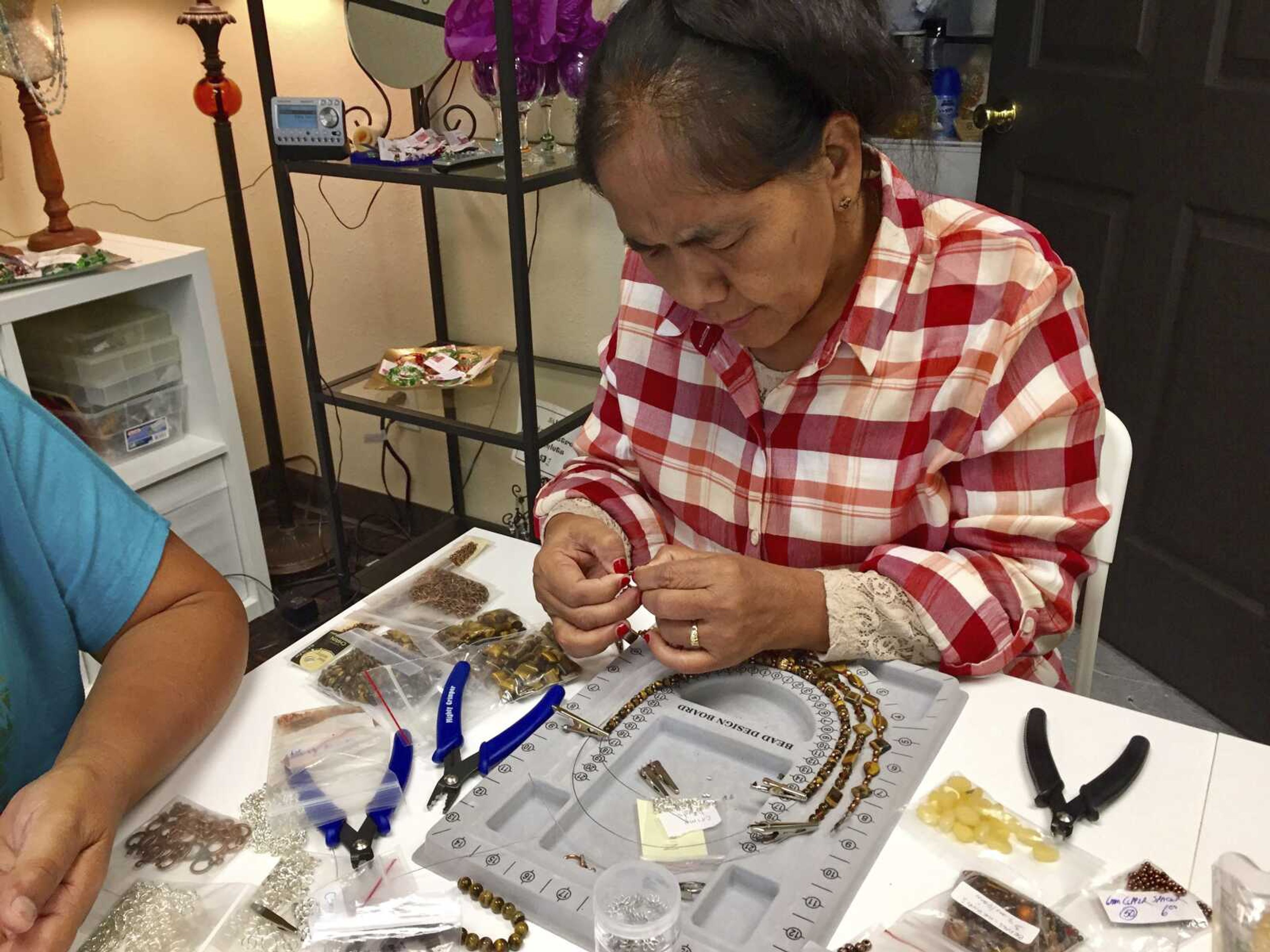 This September 2017 photo shows Niang Lam Lun from Burma focusing on mastering finishing techniques for a three-strand necklace design at A Little Something event in Aurora, Colorado. A Little Something helps women refugees turn their crafts into dollars. Around the world there are organizations that use crafting and the arts as tools to help refugees build community and learn new skills.