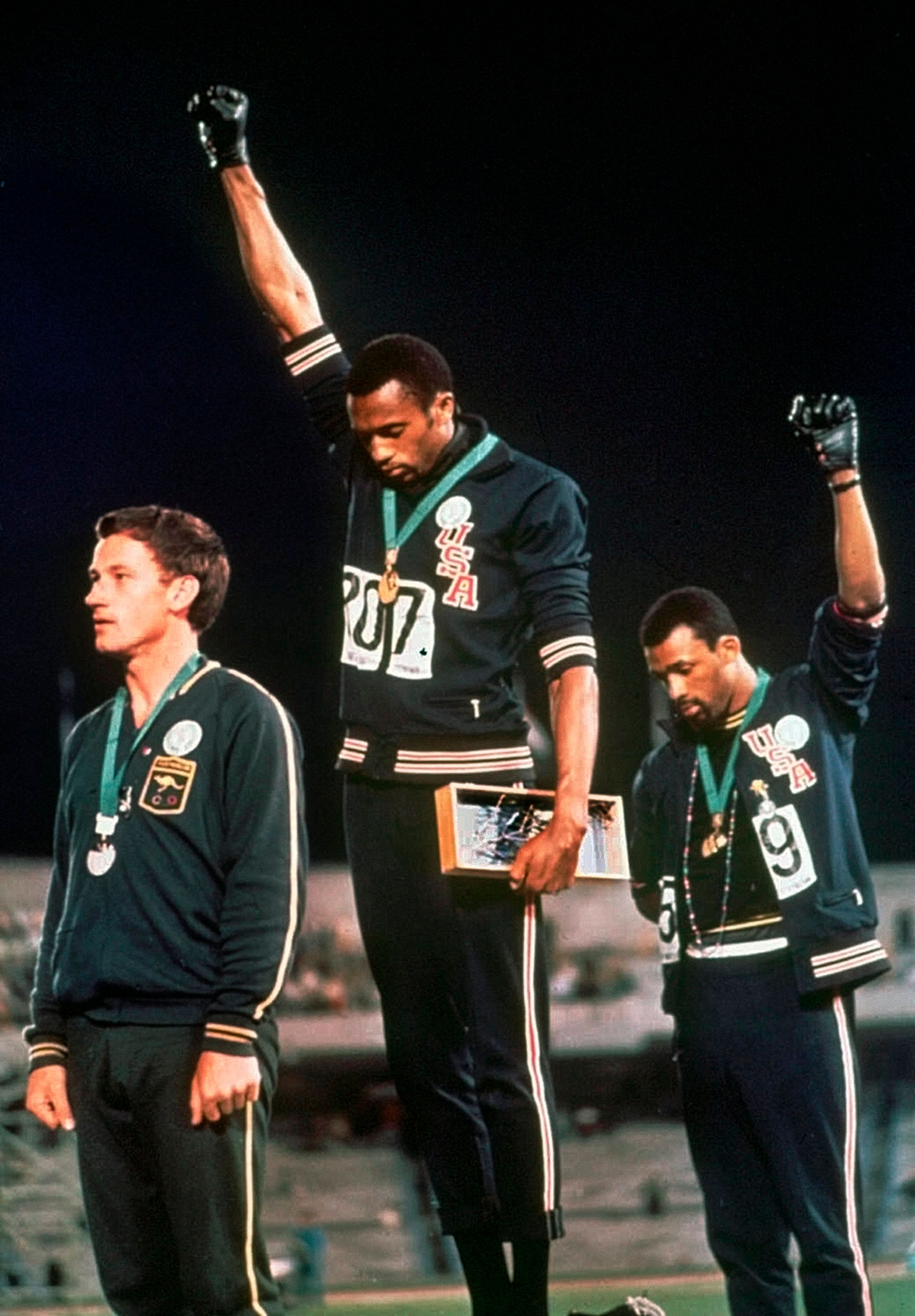 In this Oct. 16, 1968 file photo, extending gloved hands skyward in a Black power salute as a form of racial protest, U.S. athletes Tommie Smith, center, and John Carlos stare downward during the playing of national anthem after Smith received the gold and Carlos the bronze for the 200 meter run at the Summer Olympic Games in Mexico City. While the games were marked by dissent, today's situation in Mexico is much more chaotic with a government that is barely in control of many aspects of society, battered by violent drug cartels that are often supported by rogue cops and mayors. 