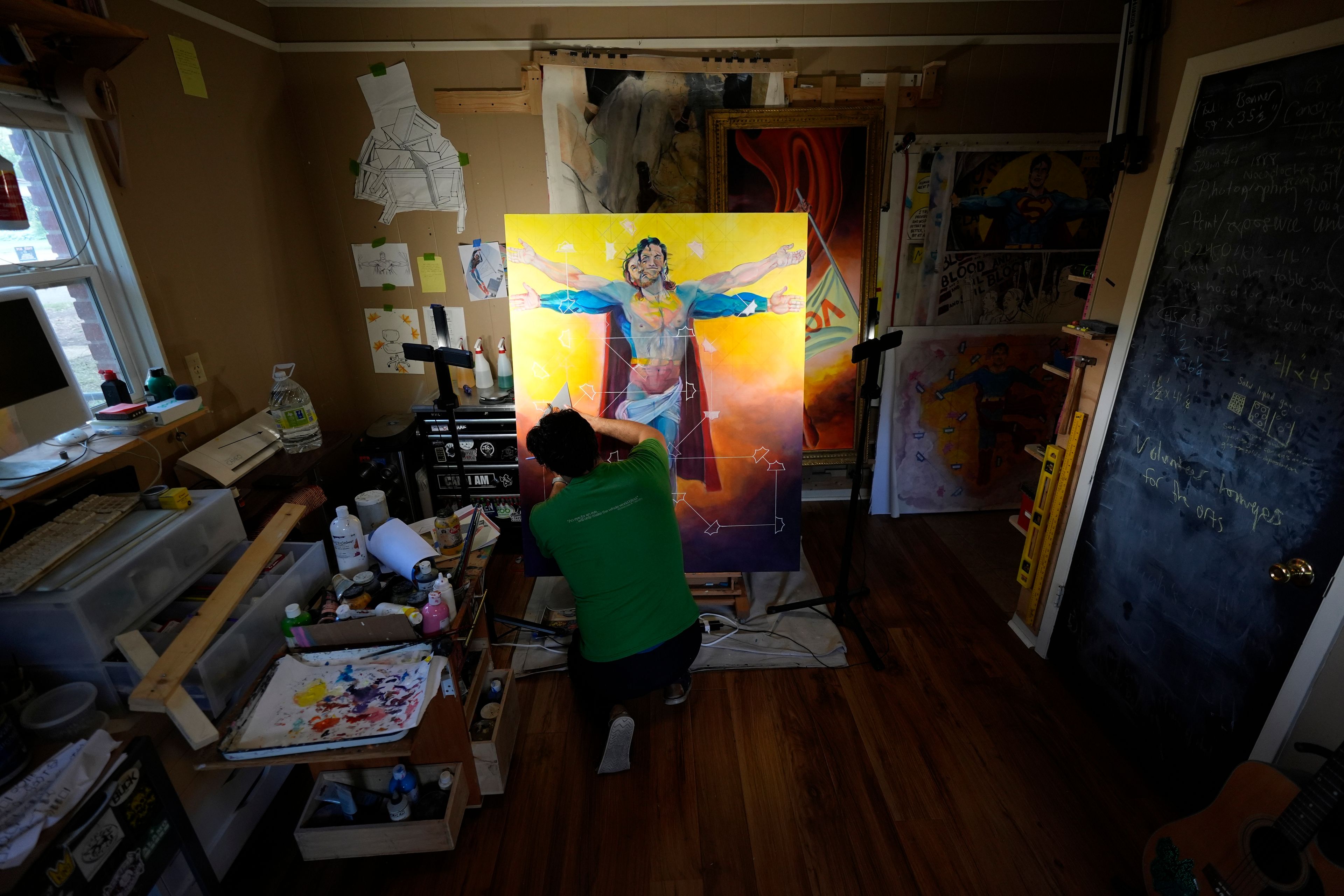 Artist David Alcantar works on an art piece for his "Superman Project" that in part encourages people to exercise their right to vote in San Antonio, Thursday, Sept. 19, 2024. (AP Photo/Eric Gay)