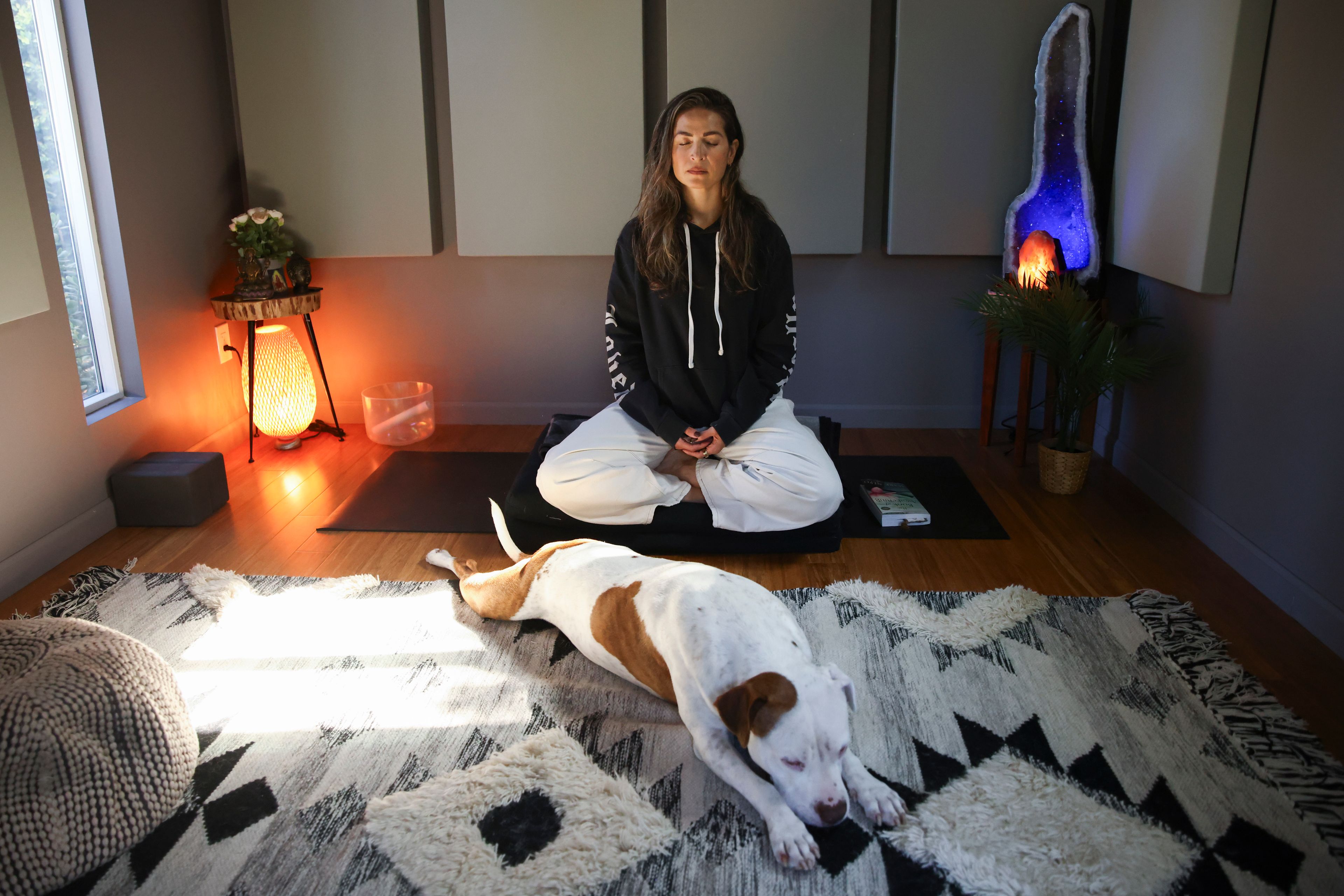 Headspace meditation teacher, Rosie Acosta, meditates in her studio with her dog Monday, Sept. 30, 2024, in Woodland Hills, Calif. (AP Photo/Jessie Alcheh)