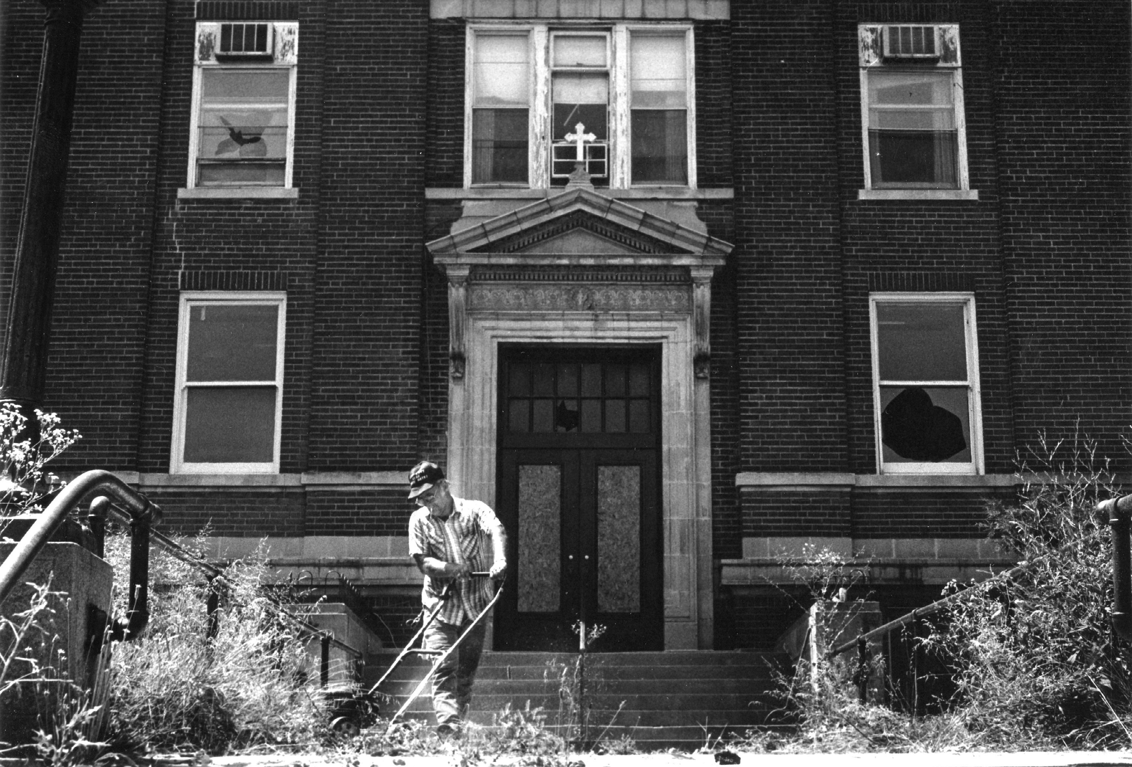 John Edwards, an employee of Rivercity Tree Service of Cape Girardeau, cuts the grass at the old Saint Francis Hospital on Good Hope Street in July 1990.