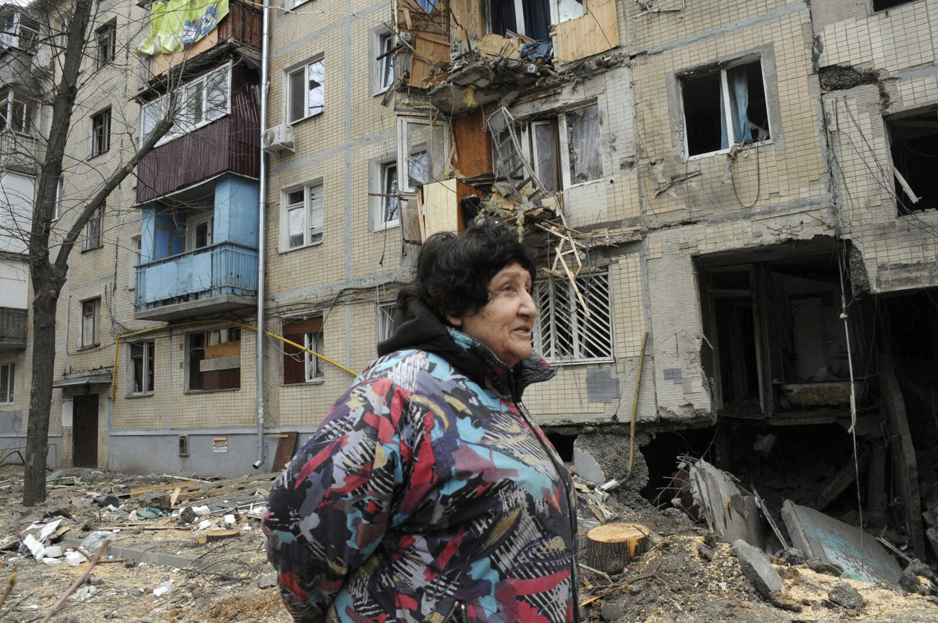 A woman walks past an apartment building damaged by shelling, Sunday in Kharkiv, Ukraine.