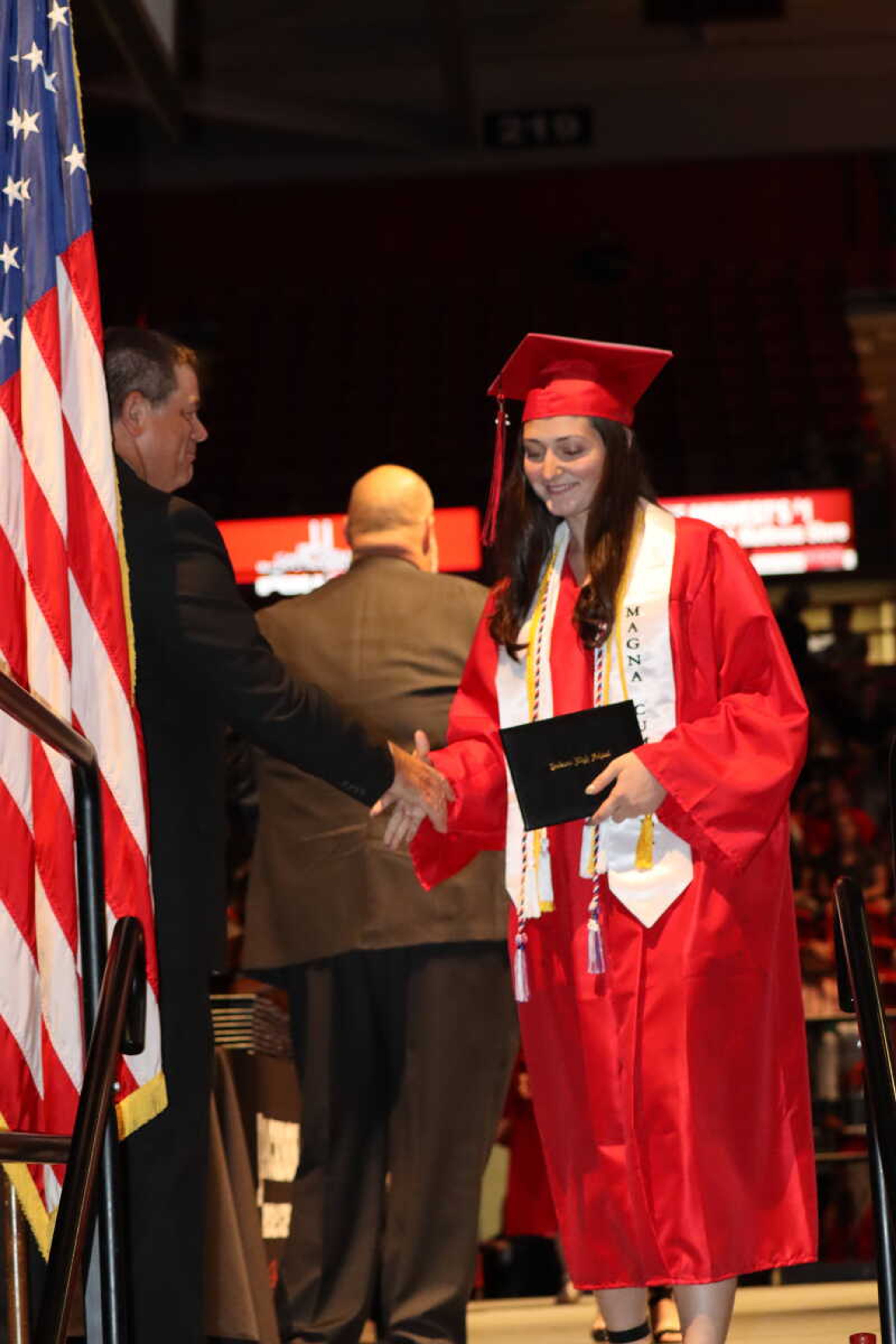 A graduate shakes hands with Superintendent Scott Smith as she makes her way of the with her new diploma.